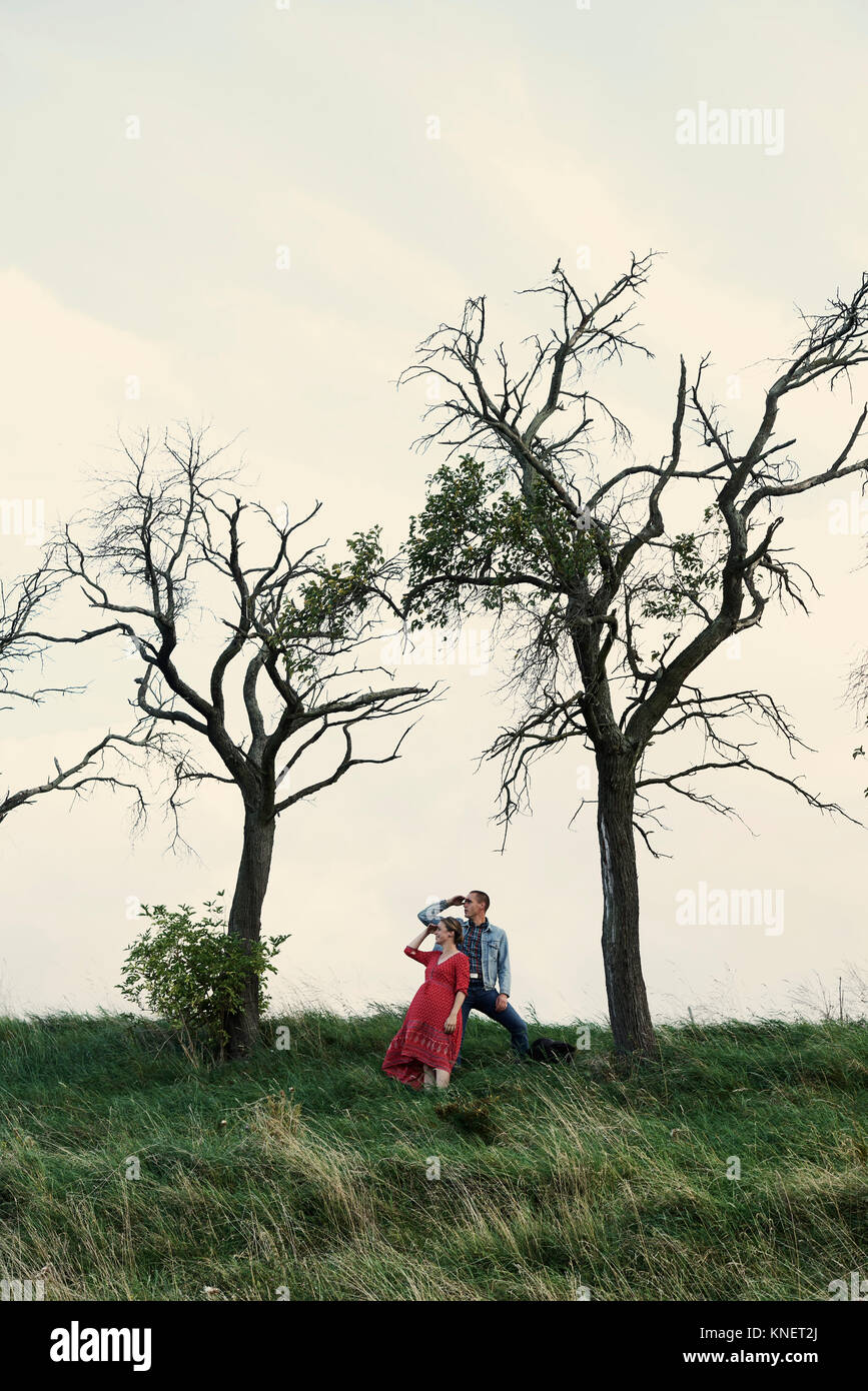 Pregnant couple looking out from hillside Stock Photo