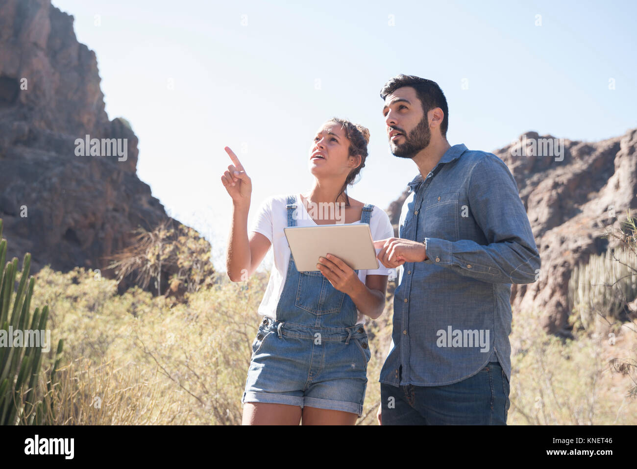 Young hiking couple looking up and pointing from valley, Las Palmas, Canary Islands, Spain Stock Photo