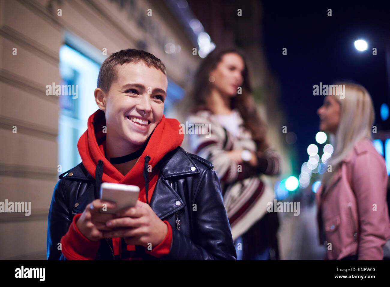 Young woman with smartphone laughing on city street at night Stock ...
