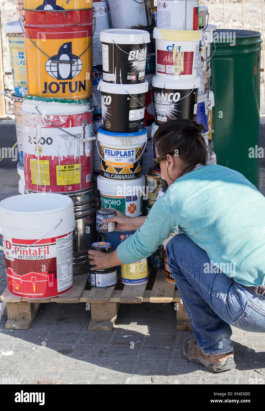 Spanish woman disposing of pain tins at council recycling centre in  Spain. Stock Photo