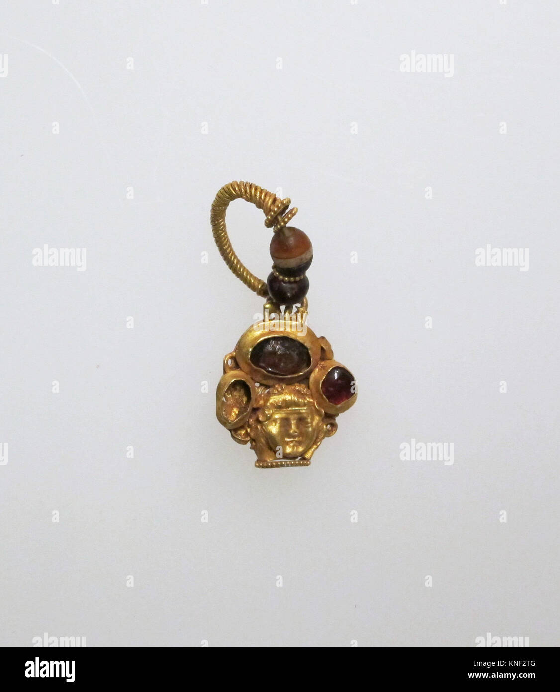 Earring with human face. Date: 1st century B.C.-3rd century A.D; Culture: Roman; Medium: Gold, garnet; Dimensions: Other: 9/16 x 11/16 x 1 1/2 in. Stock Photo
