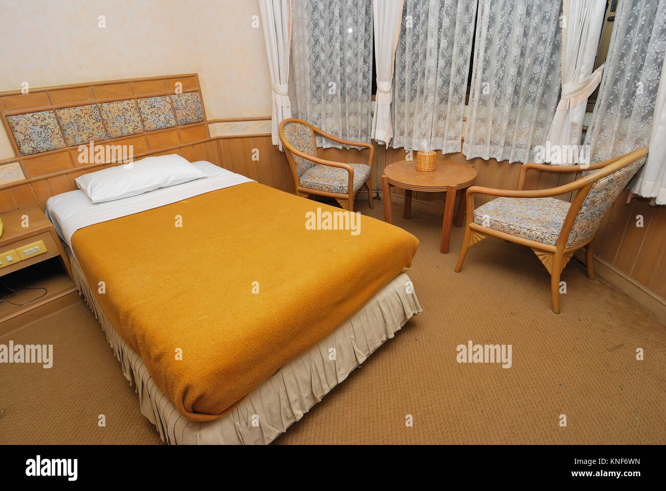 Single bed neatly done up in a high class hotel room with table and chairs. Suitable for concepts such as travel, tourism, vacation and holiday. Stock Photo