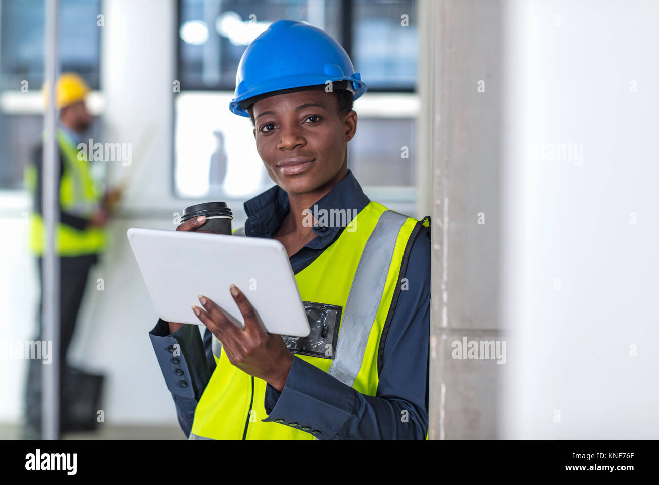 Woman with hard hat and hi viz jacket using digital tablet Stock Photo