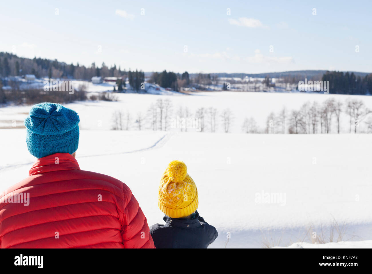 Rear view of man and son looking out over snow covered landscape Stock ...