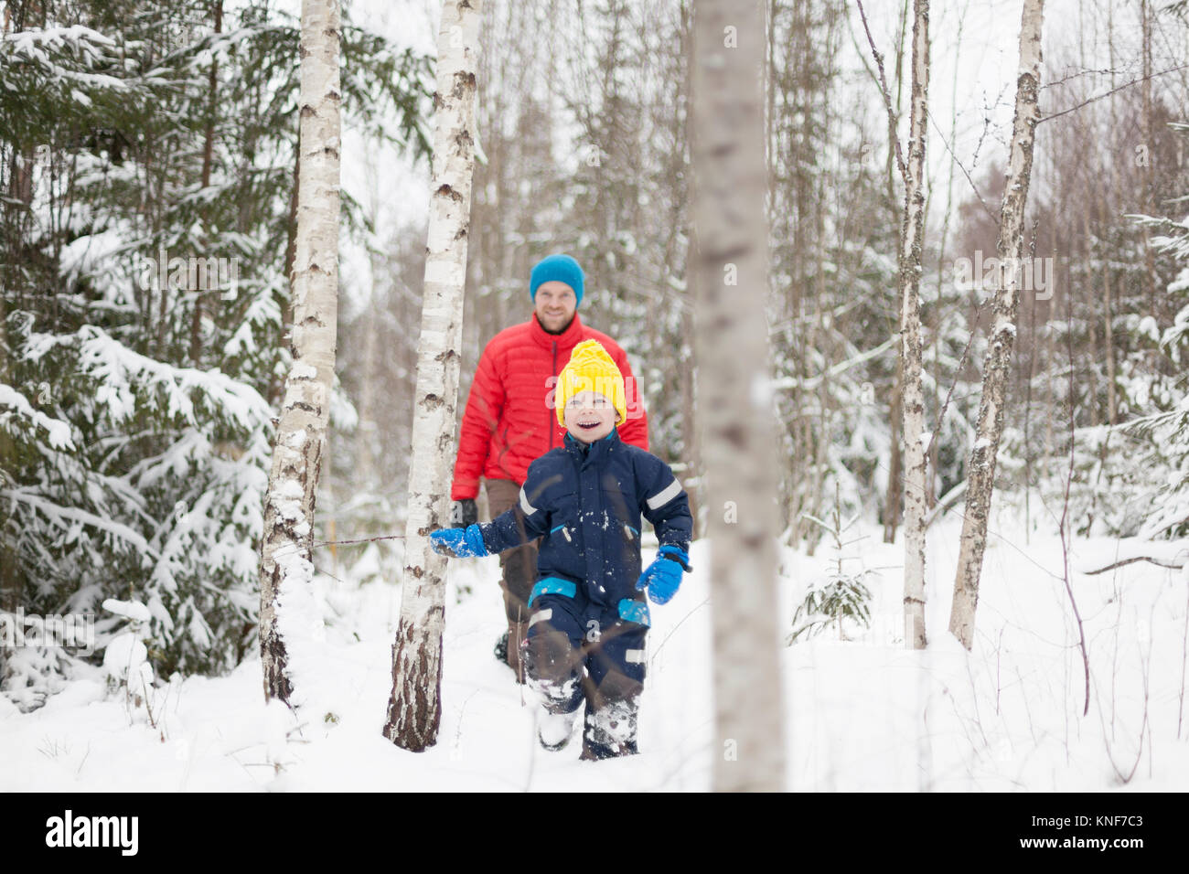Man and son walking in snow covered forest Stock Photo
