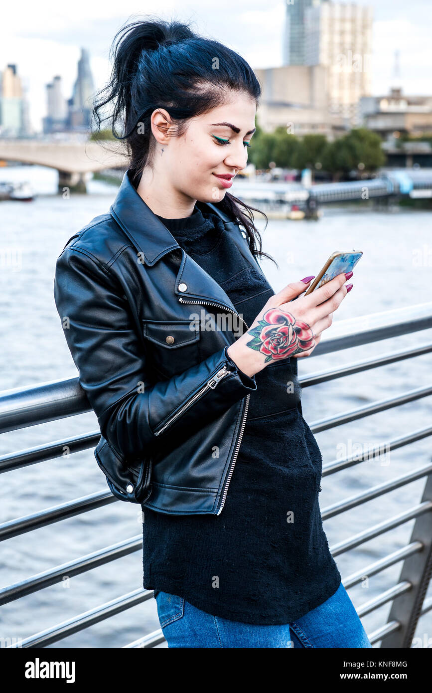 Young woman looking at smartphone on millennium footbridge, London, UK Stock Photo
