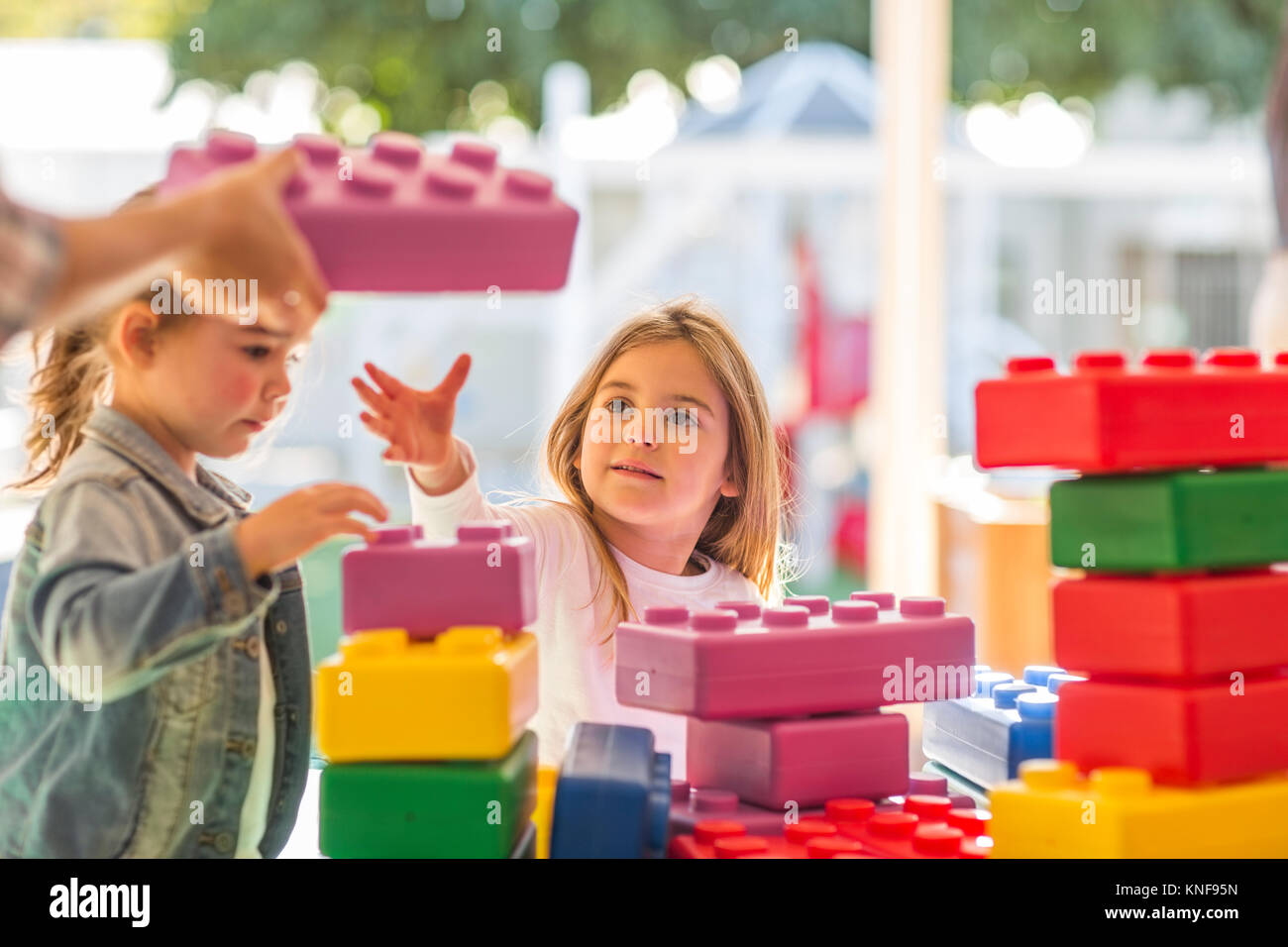 Two young children, outdoors, playing with foam building blocks Stock