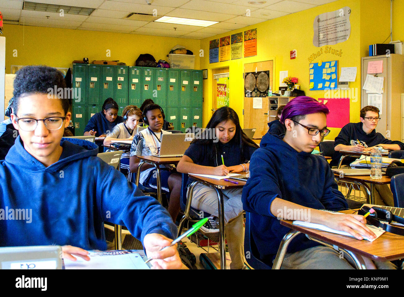 Class of teenage boys and girls doing schoolwork at classroom desks Stock Photo