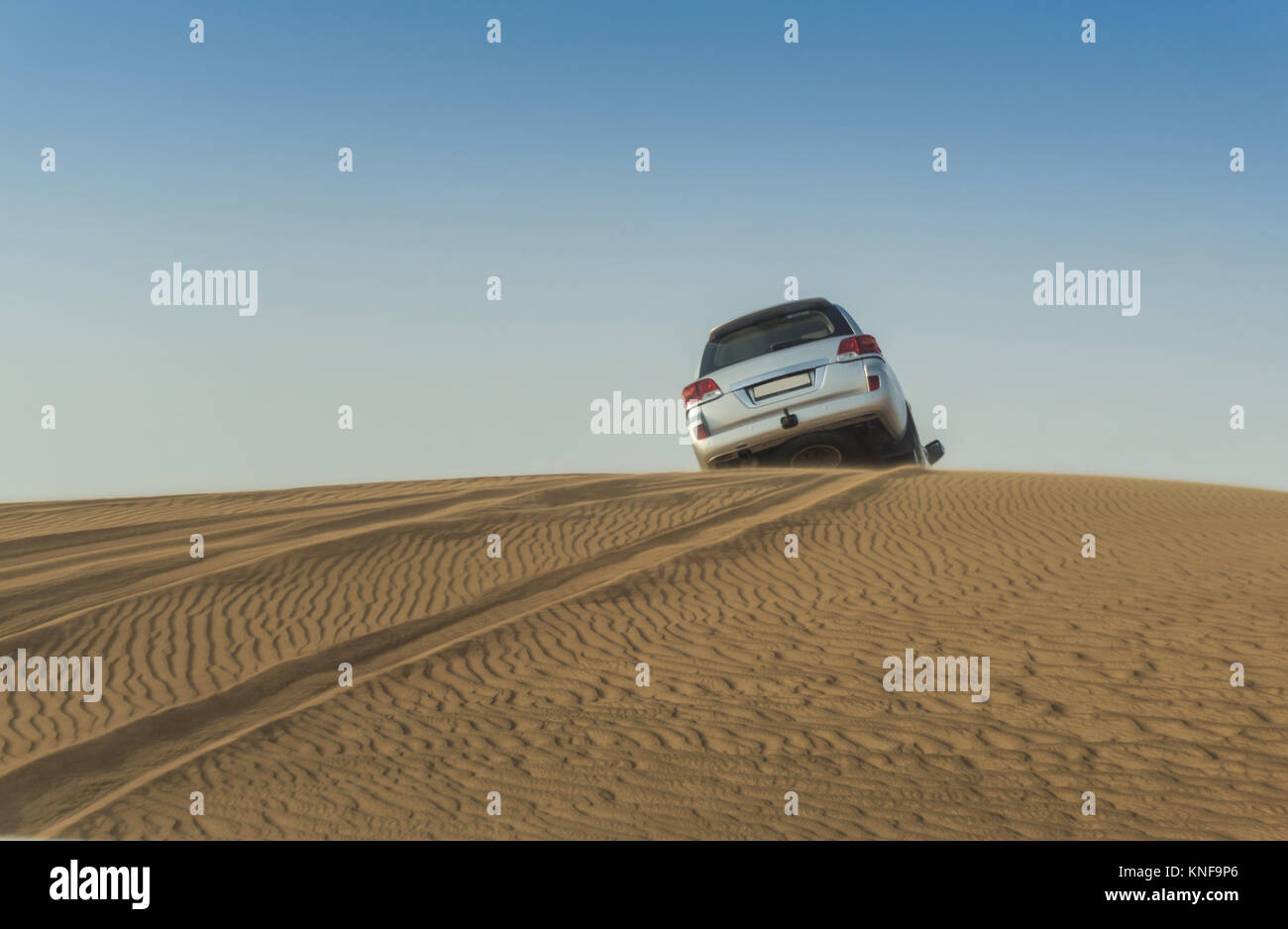 Off road vehicle driving over top of desert dunes, Dubai, United Arab
