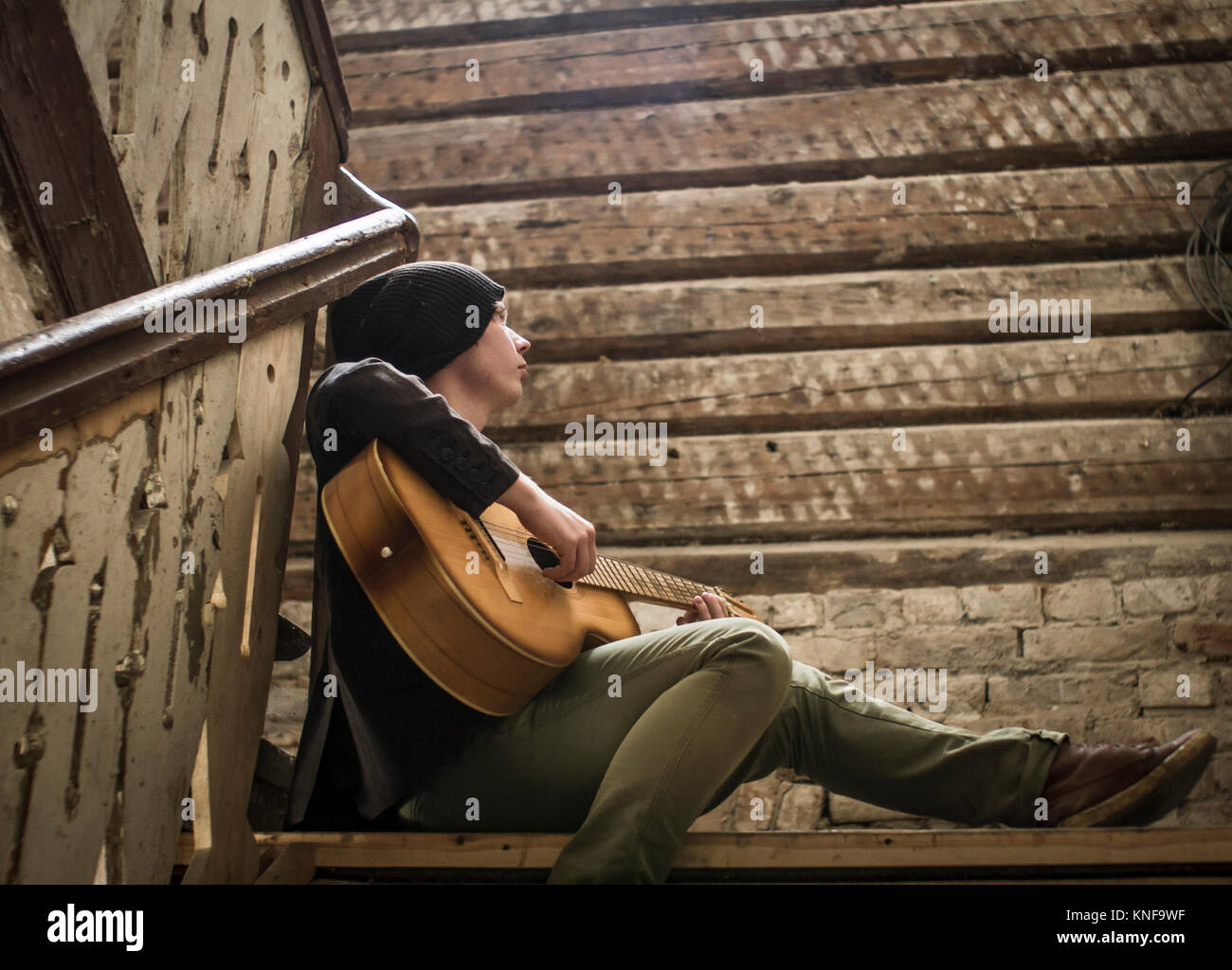 Young man sitting on stairs, playing guitar Stock Photo