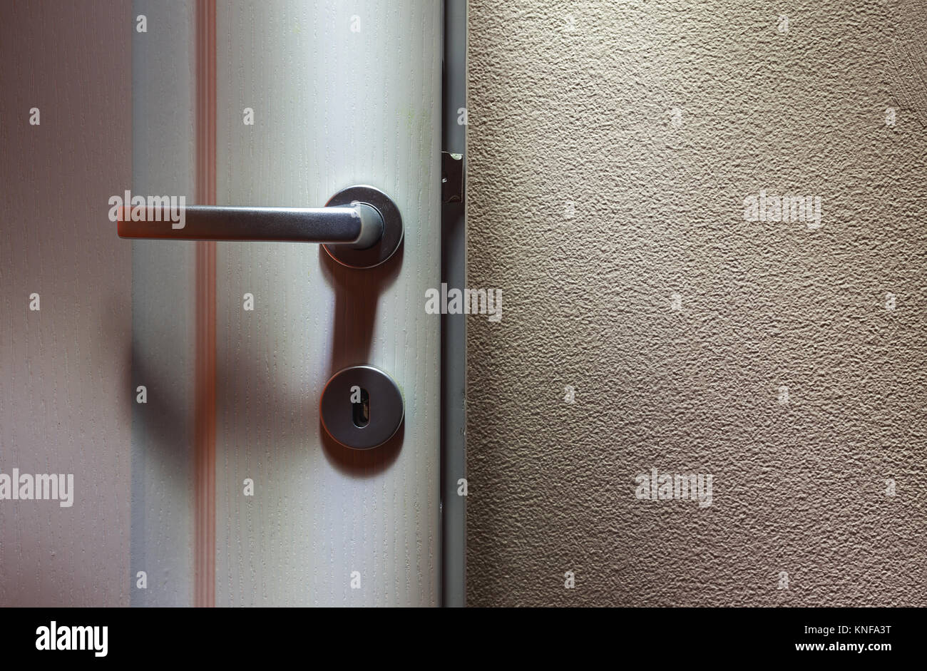 Abstract of white wooden door and door lock on one side and empty wall on other. Stock Photo