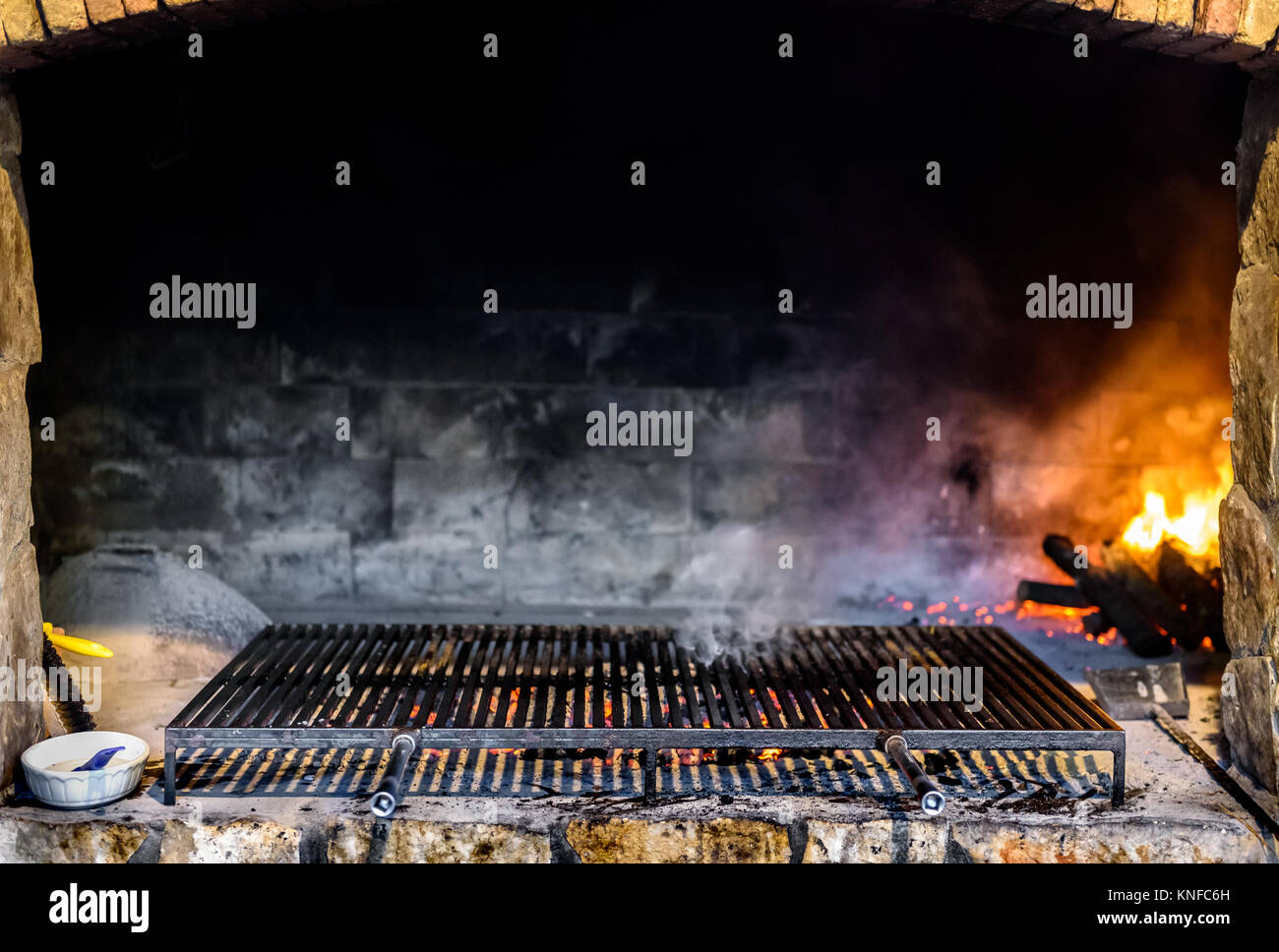 Professional big stone paved barbecue fireplace grill in a restaurant. Grilling on charcoal or coal with big grill grates or grids, and burning wood i Stock Photo