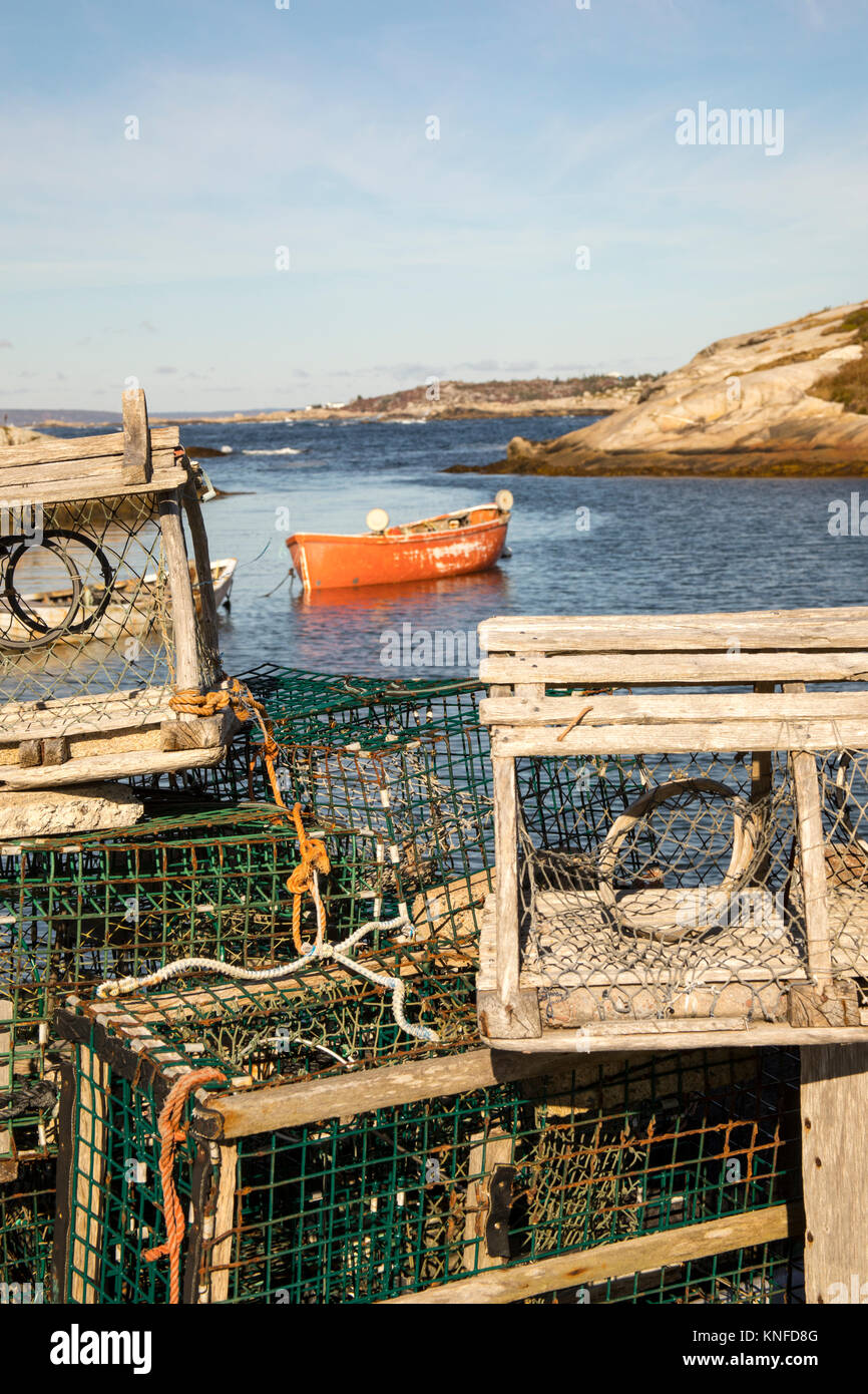 Wooden lobster traps on pier in Peggy's Cove, Nova Scotia, Canada with boat in marina on sunny day. Stock Photo