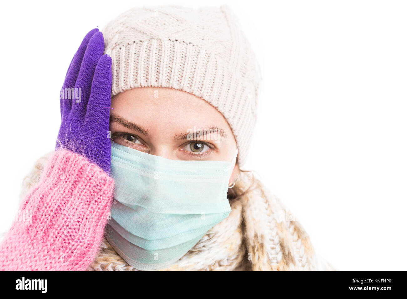 Unwell woman holding her head because of winter flu virus and wearing warm knitted hat and scarf Stock Photo