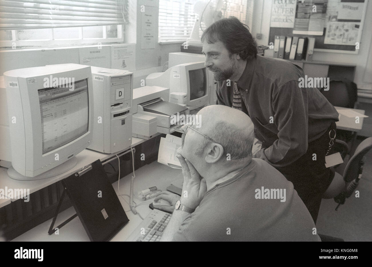 Male prison inmate (seated) assisted by tutor learning computer skills