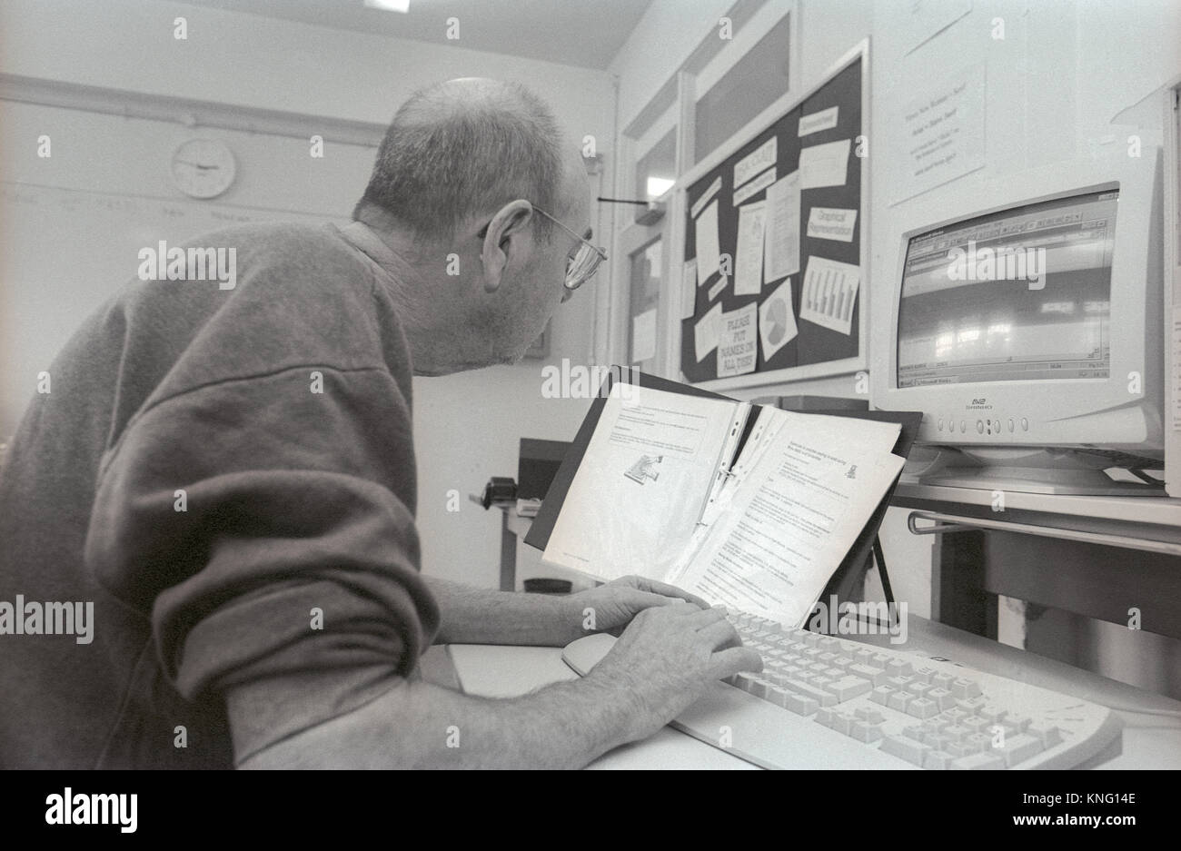 Male prison inmate learning computer skills in education room at HMP