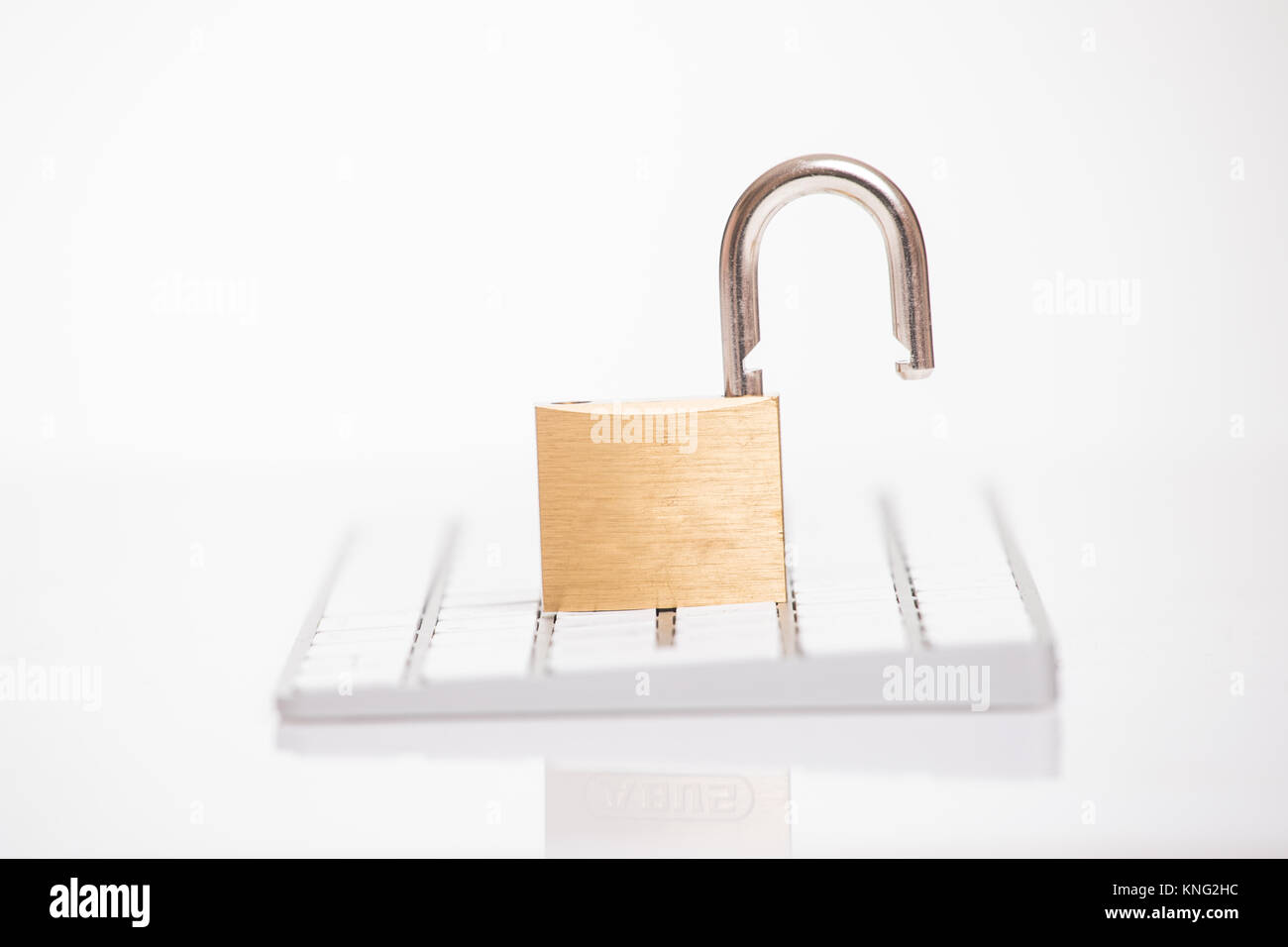 Open steel padlock lying on a white computer keyboard in a low angle view in a concpet of privacy Stock Photo