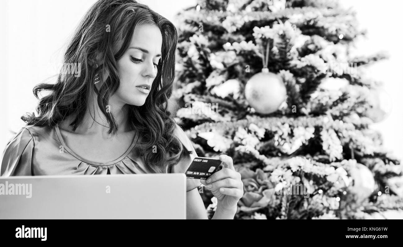 Young woman making online shopping near christmas tree Stock Photo