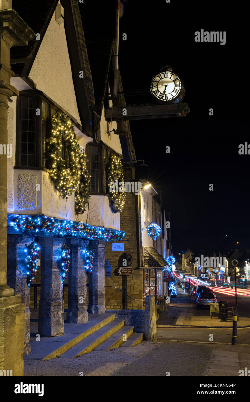 Christmas wreath decorations and lights on the Tolsey Museum at night. Burford, Cotswolds, Oxfordshire, England Stock Photo