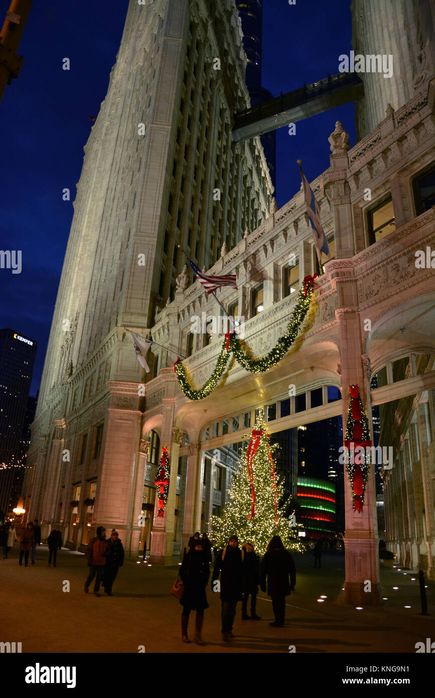 Holiday shoppers on Michigan Avenue's 'Magnificent Mile' walk past the Christmas lights on the Wrigley Building on a brisk evening in Chicago. Stock Photo