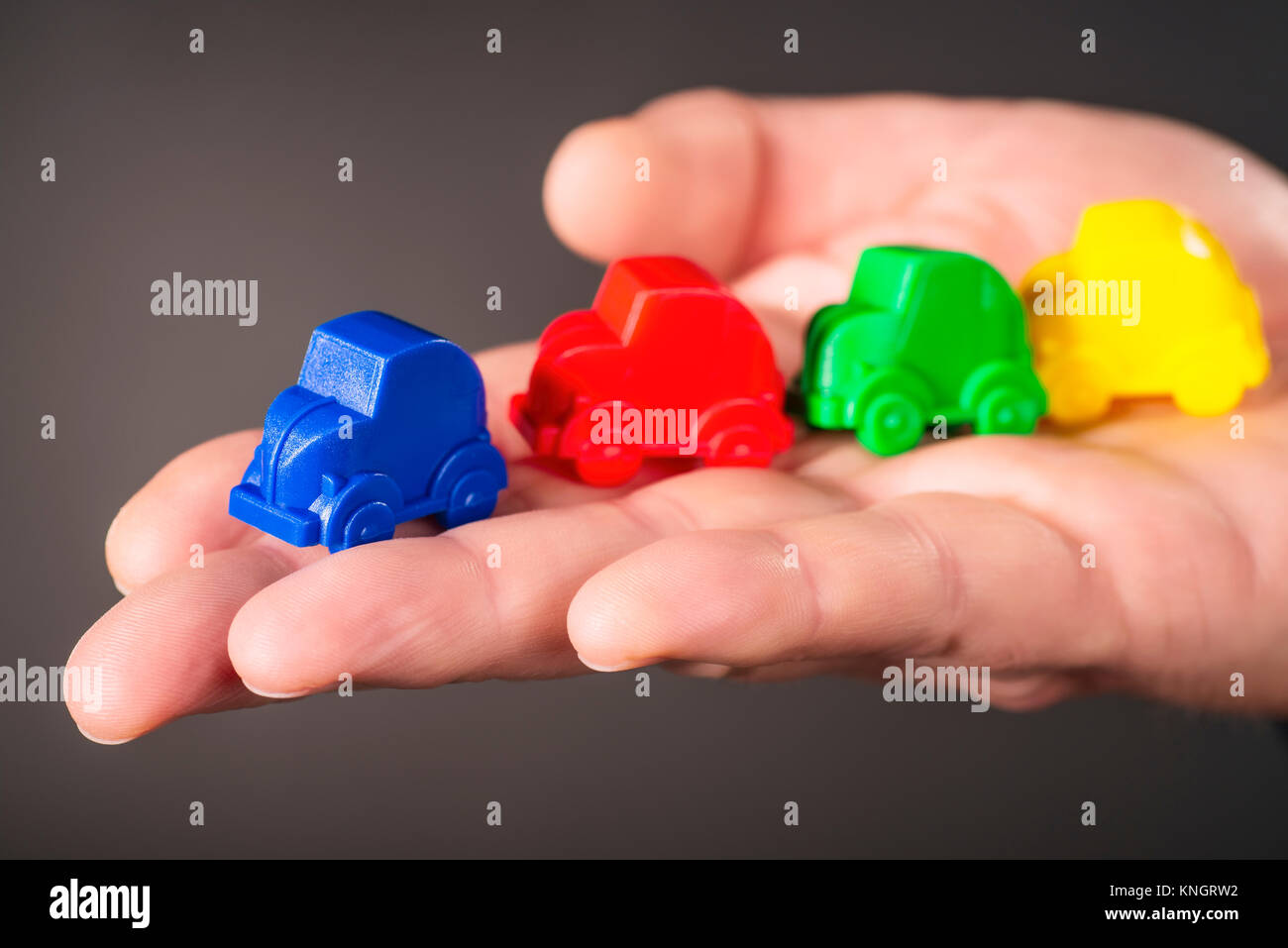 Toy cars in the colors blue, red, green and yellow are carried on a palm. Stock Photo