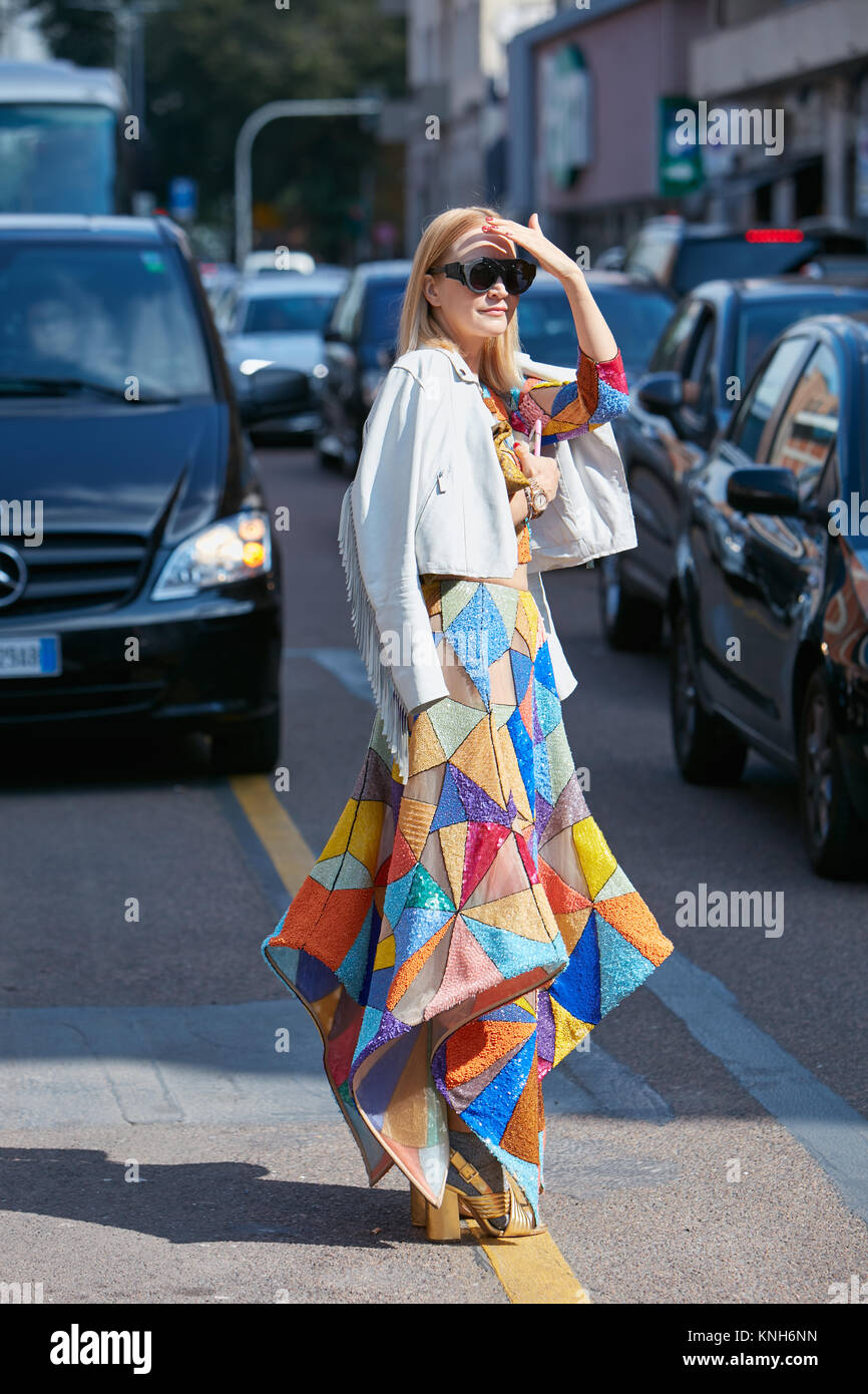MILAN - SEPTEMBER 24: Woman with colorful glitter geometric skirt and white jacket before Trussardi fashion show, Milan Fashion Week street style on S Stock Photo