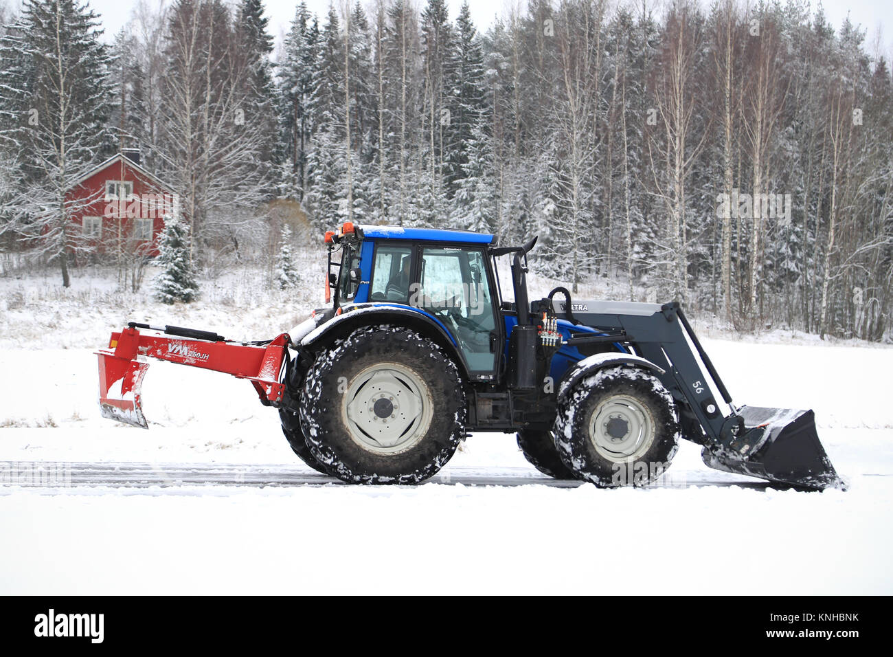 SALO, FINLAND – NOVEMBER 22, 2014: Valtra tractor removes snow with bucket and VM  road drag.  In Finland, snow removal expenses can be considerable. Stock Photo