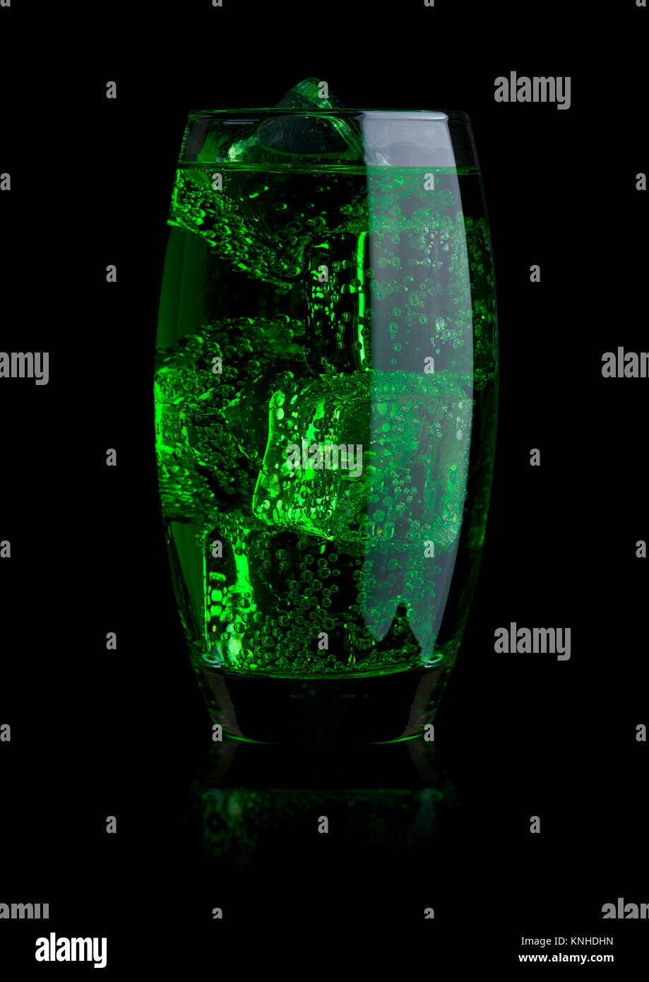 Glass of blue energy carbonated soda drink with ice on black background ...