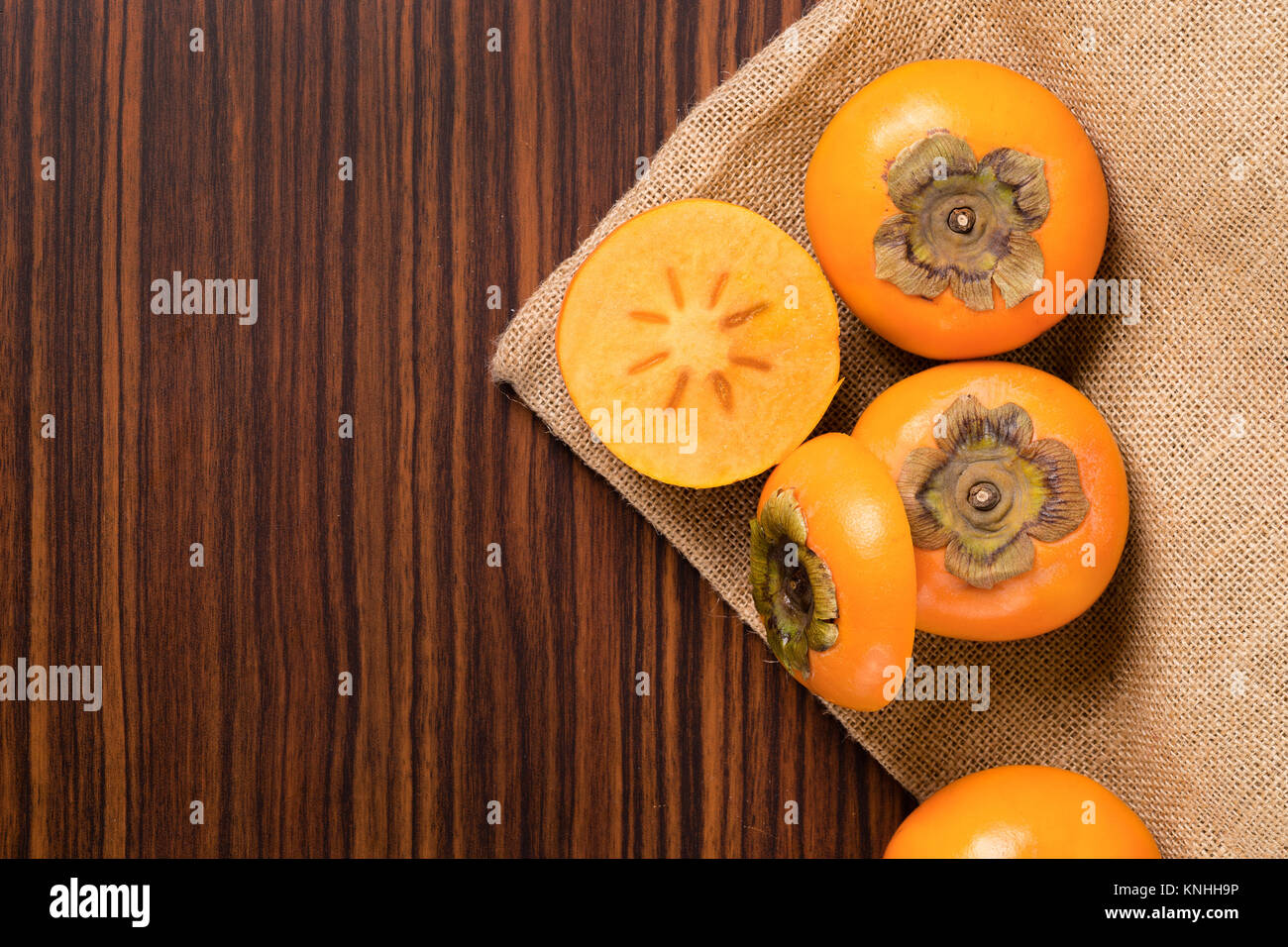 Persimmon fruit on rustic sack and wooden table Stock Photo