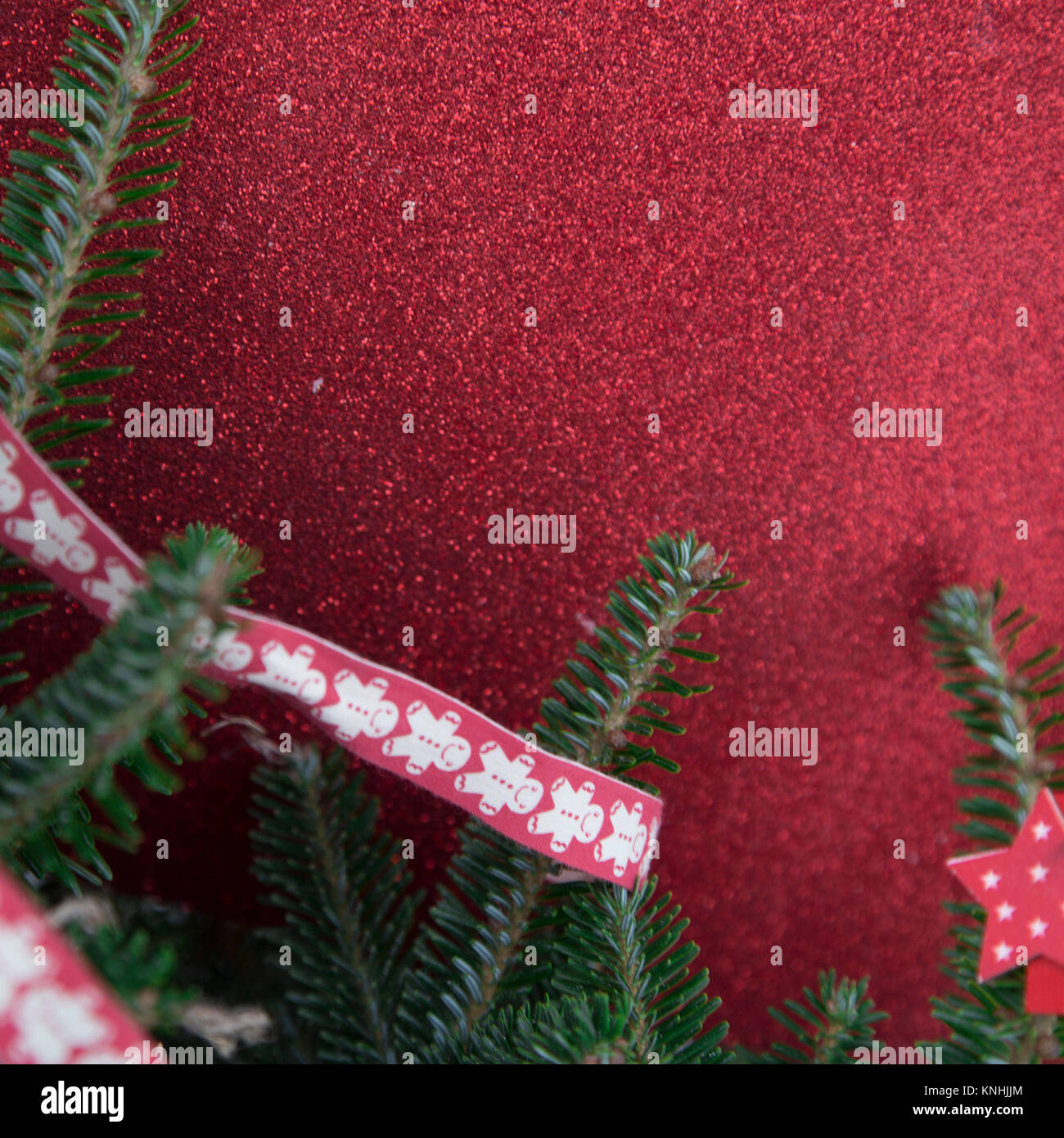 Red glitter Christmas background with fir tree branch and a red ribbon