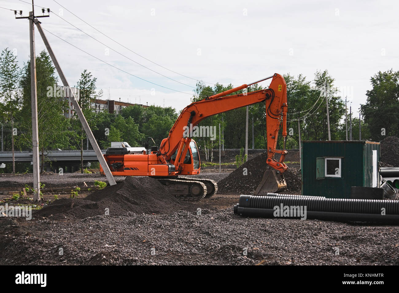 excavator on construction site, in the background the blue sky and sun ...