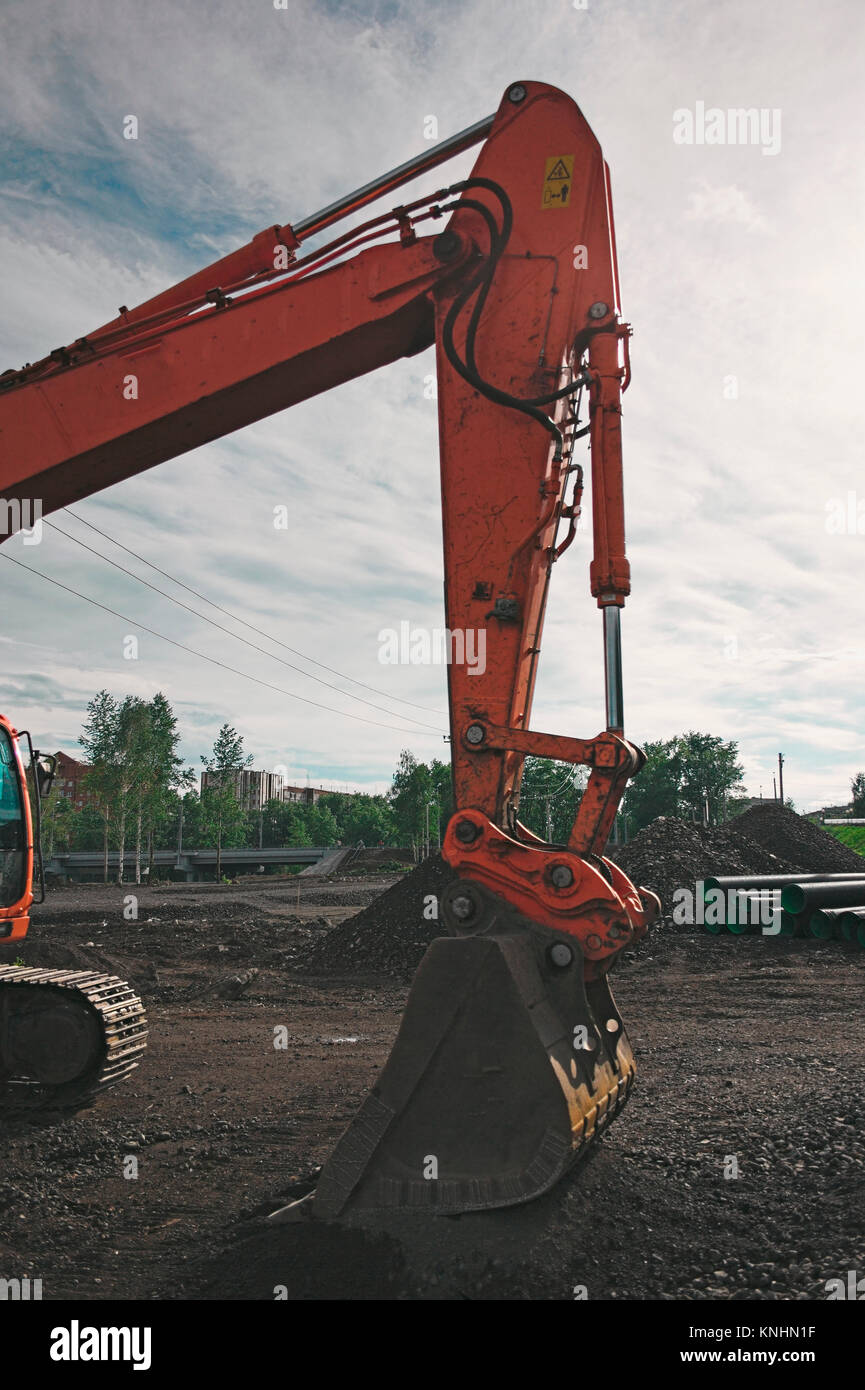 excavator on construction site, in the background the blue sky and sun ...