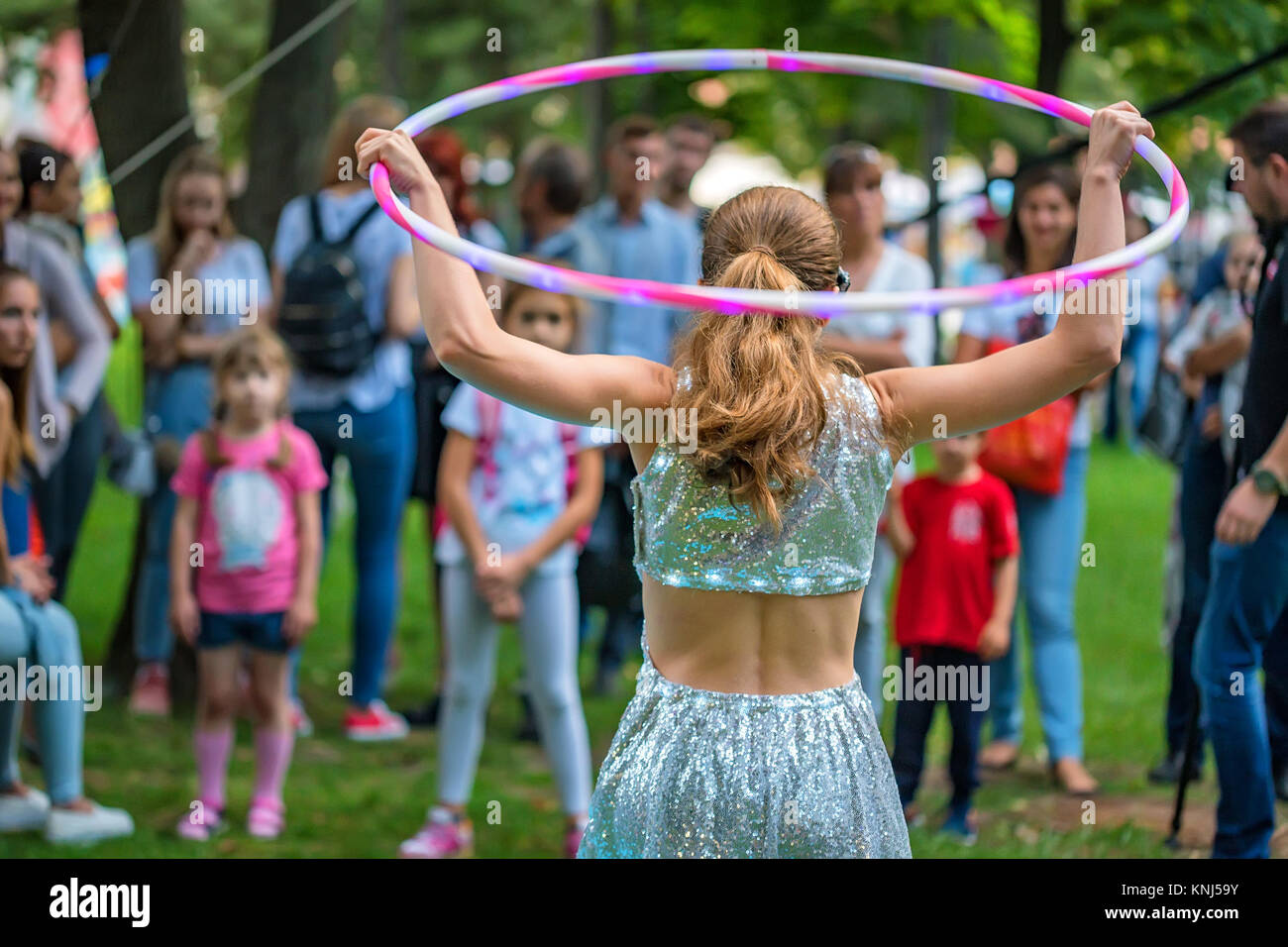 Girl in beautiful dress performs with hula hoops Stock Photo