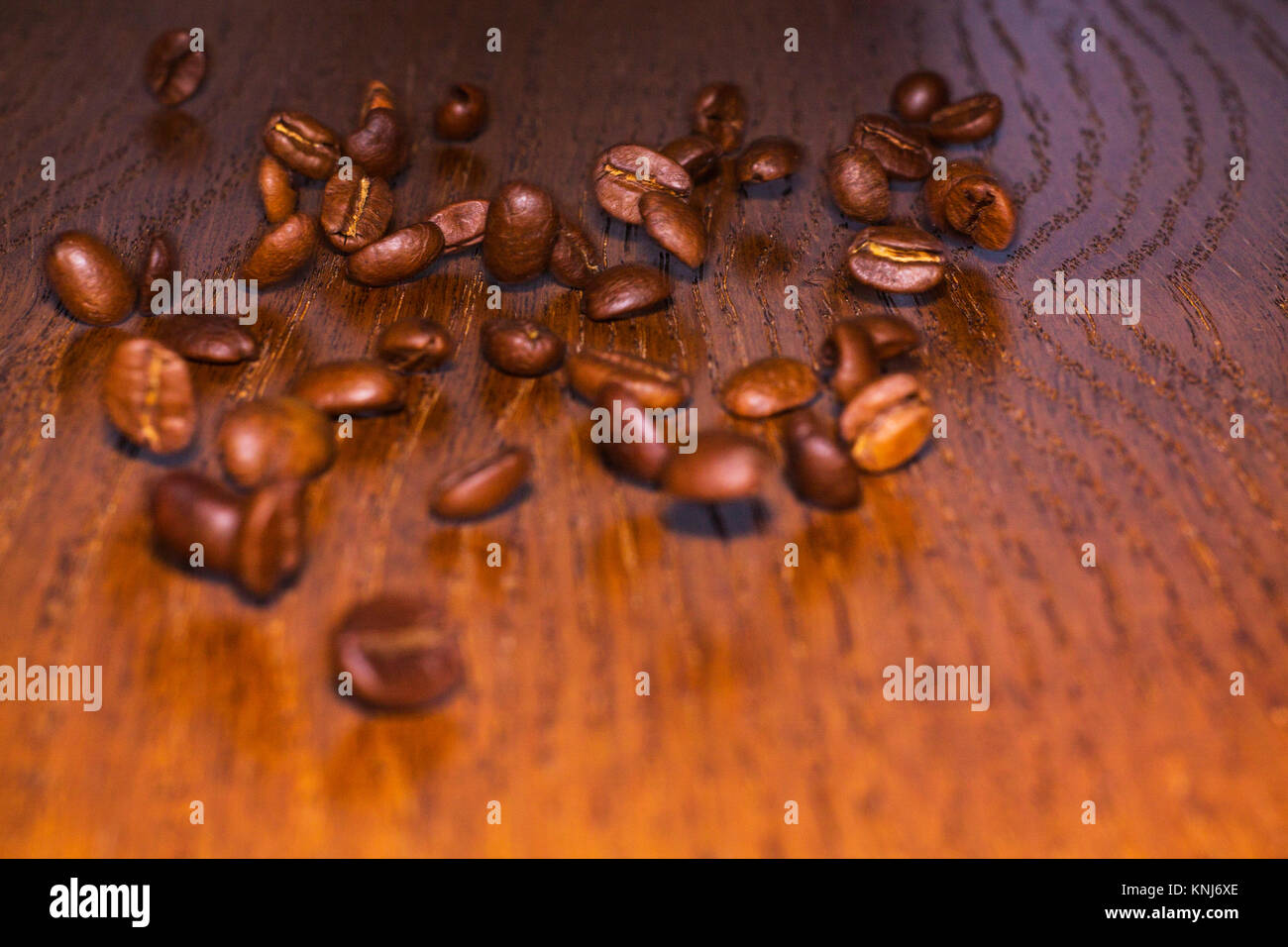 Grains of roasted coffee rolling on a wooden table Stock Photo Alamy