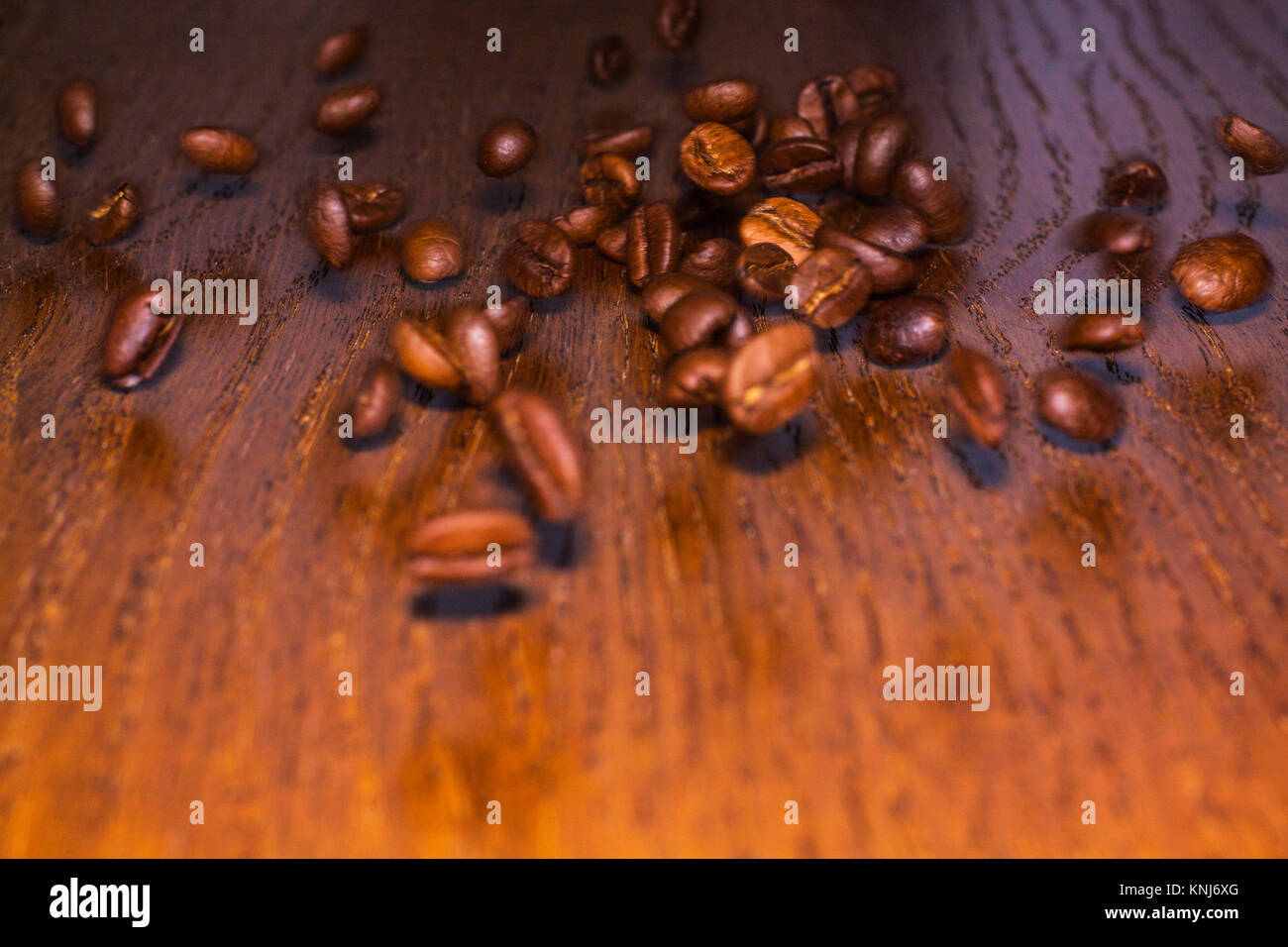 Grains of roasted coffee rolling on a wooden table. Stock Photo