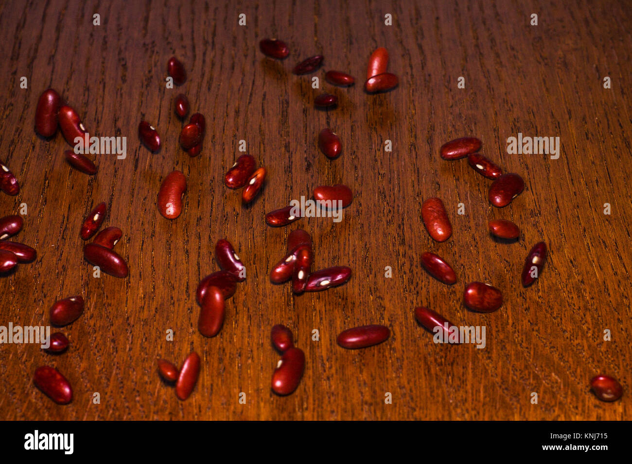 Many kidney beans roll down the wooden table. Stock Photo