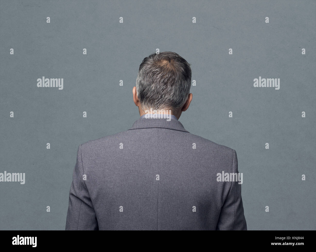 Businessman standing on a gray background, back view Stock Photo - Alamy