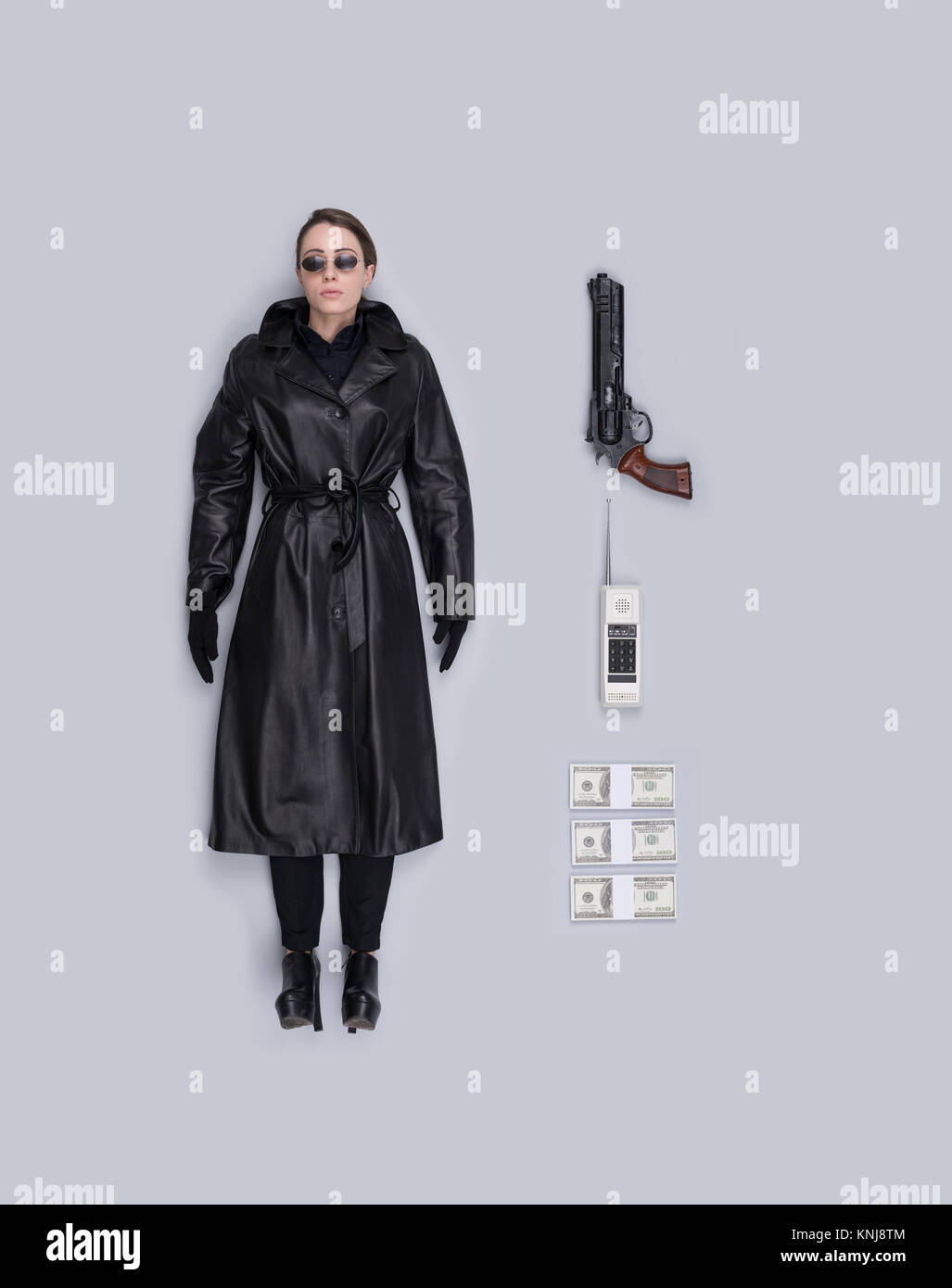 Lifelike female spy agent human doll with leather coat, gun and accessories, flat lay Stock Photo