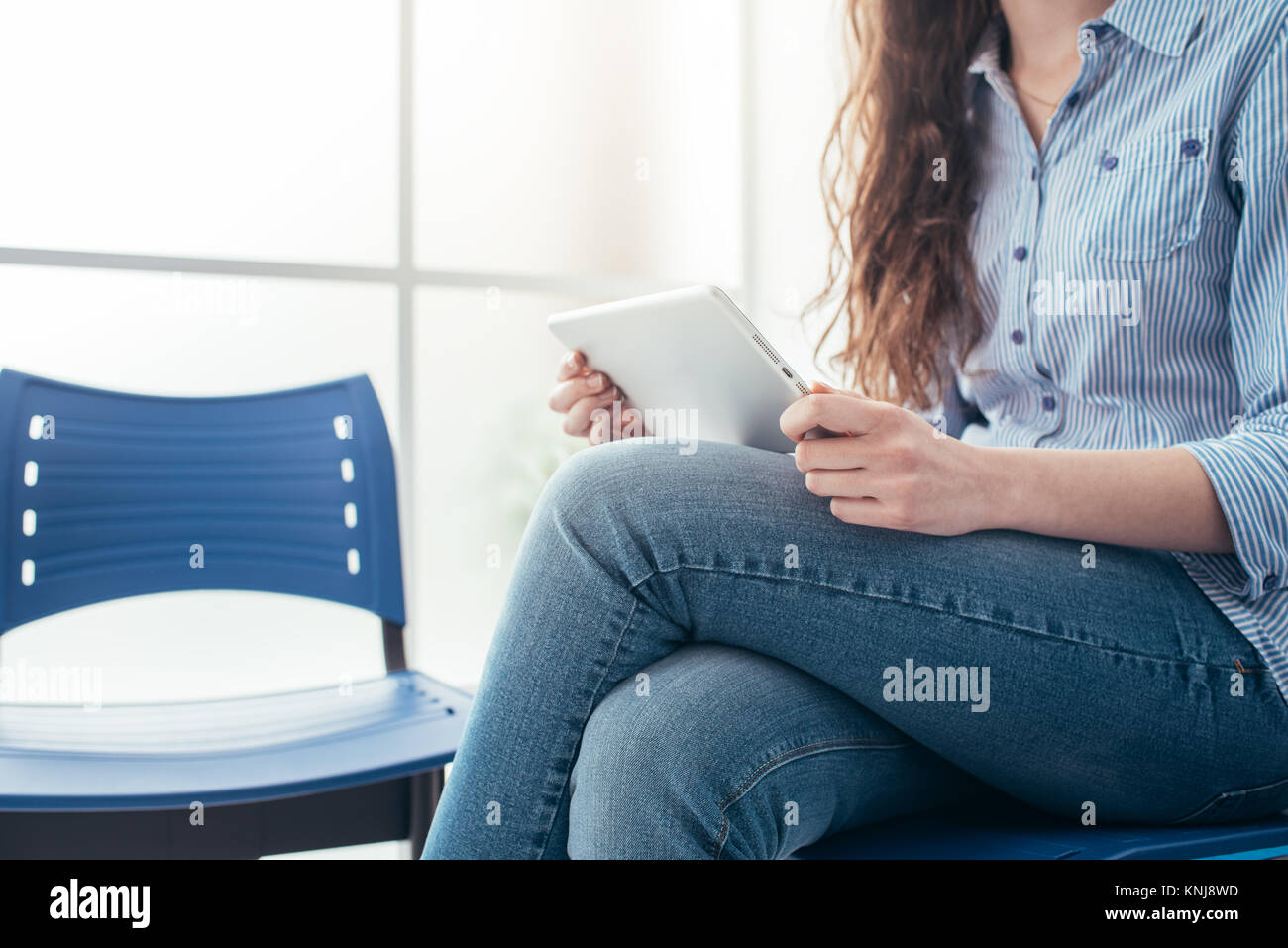 Young woman sitting in the waiting room and connecting with a touch ...