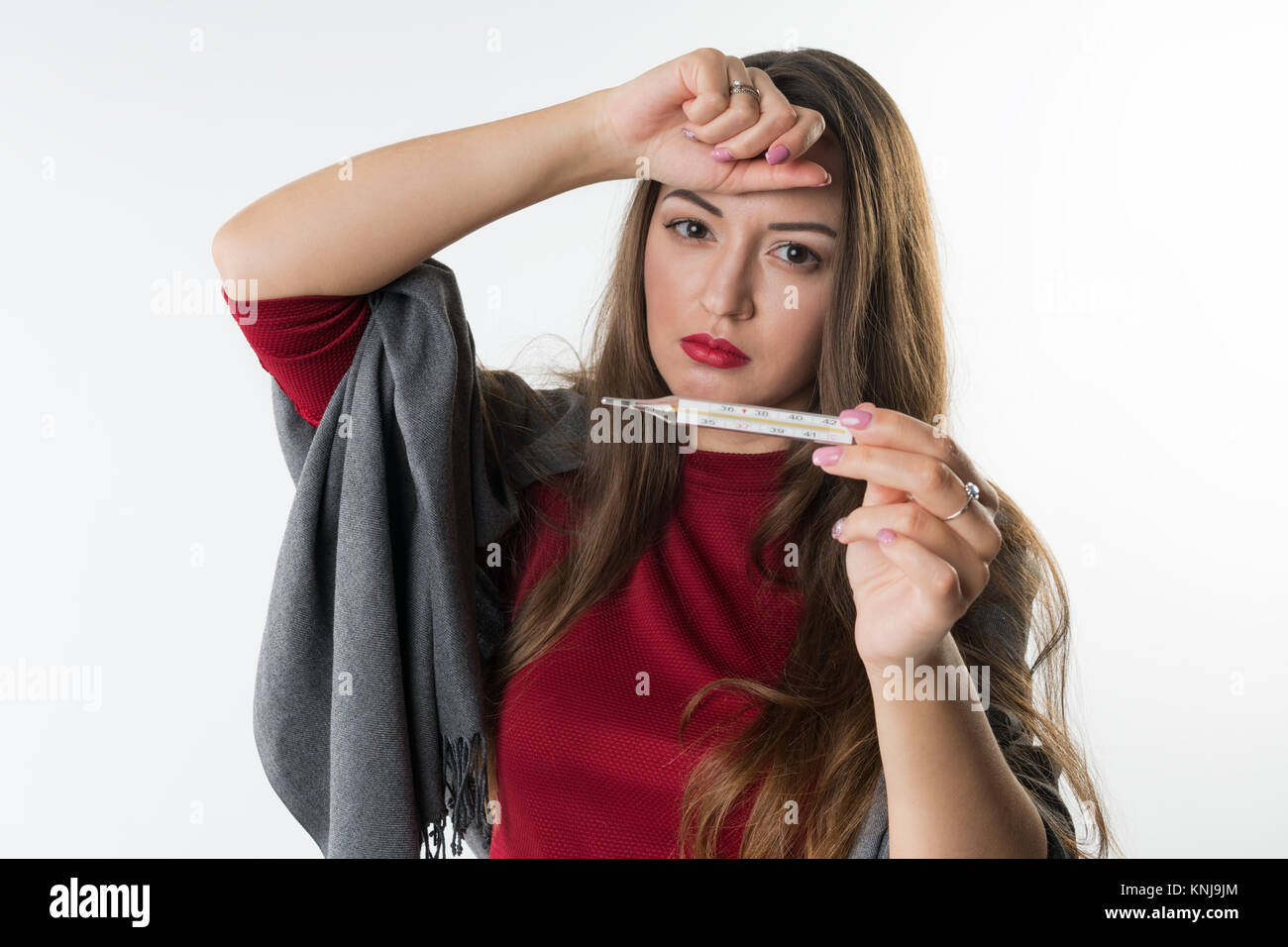 sick woman checking her temperature . She has cold and fever Stock Photo