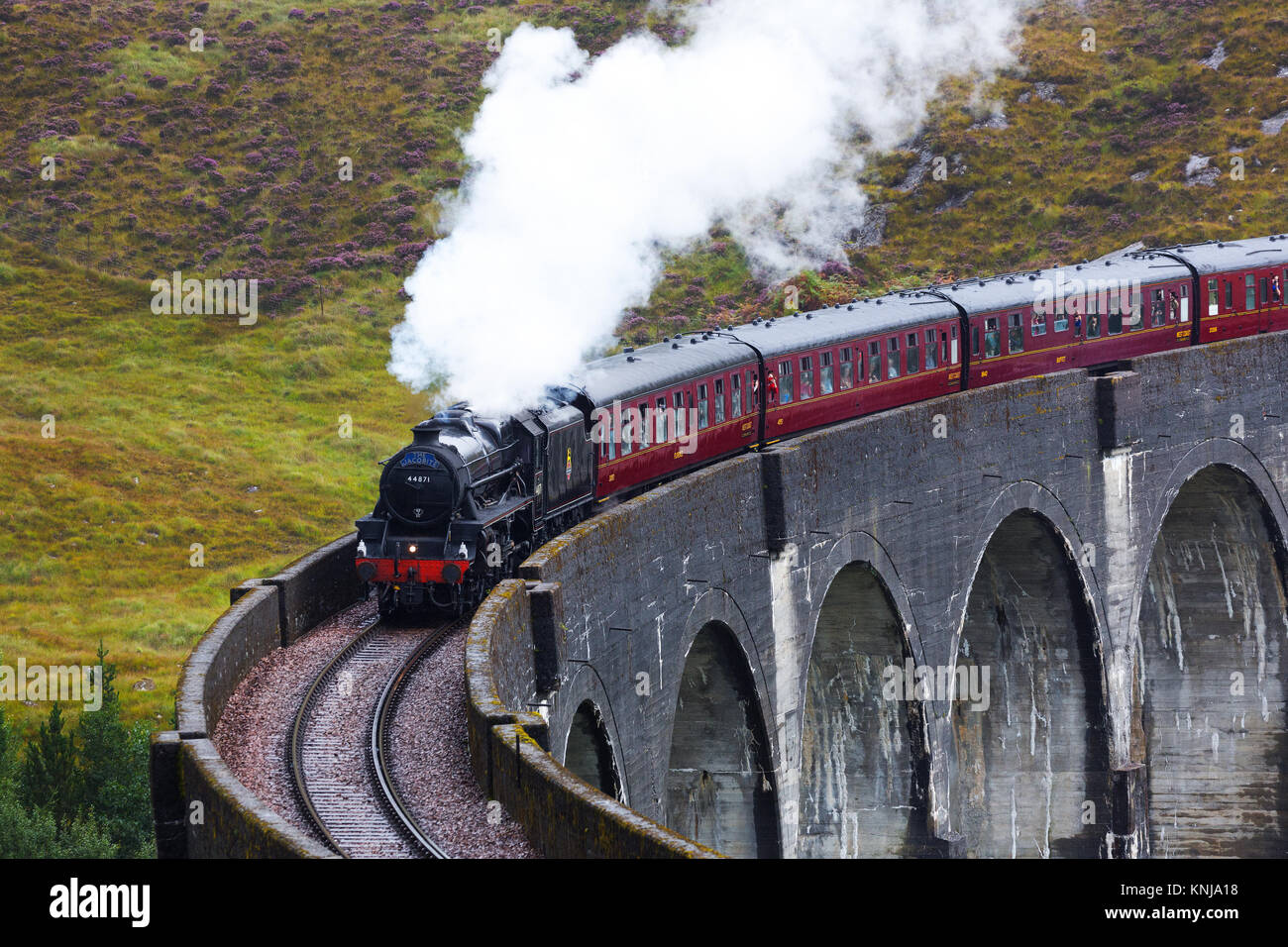 The Hogwarts Express steam train passing on Glenfinnan viaduct, Lochaber, Highland of Scotland, UK Stock Photo