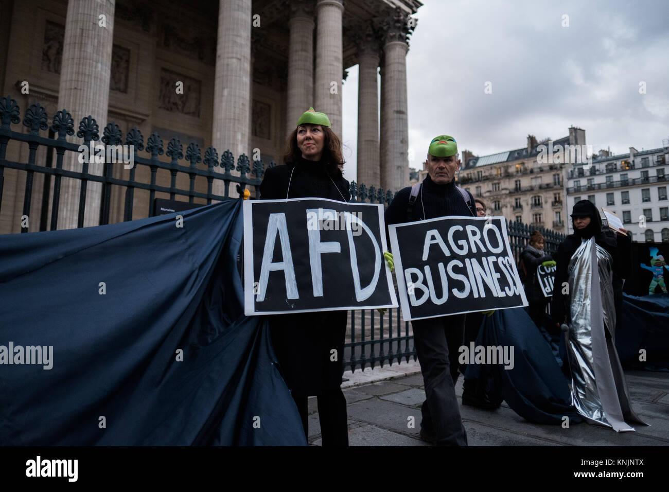 Paris, Ile de France, France. 12th Dec, 2017. Protesters prepare for the incoming action, displaying placards calling out the AFD (French Agency for Development) and the agro industry. Answering a call from 350 France, Tour Alternatiba, Les Amis de la Terre France, ANV Action non-violente COP21, Attac France (Officiel), Bizi Mugi, le CRID, le Réseau Action Climat, la Fondation pour la Nature et l'Homme, Oxfam France, Refedd et ZEA, several hundred protesters gathered in front of the Panthéon in Paris for happening. They symbolically tore down the 'wave of energies from the pa Stock Photo