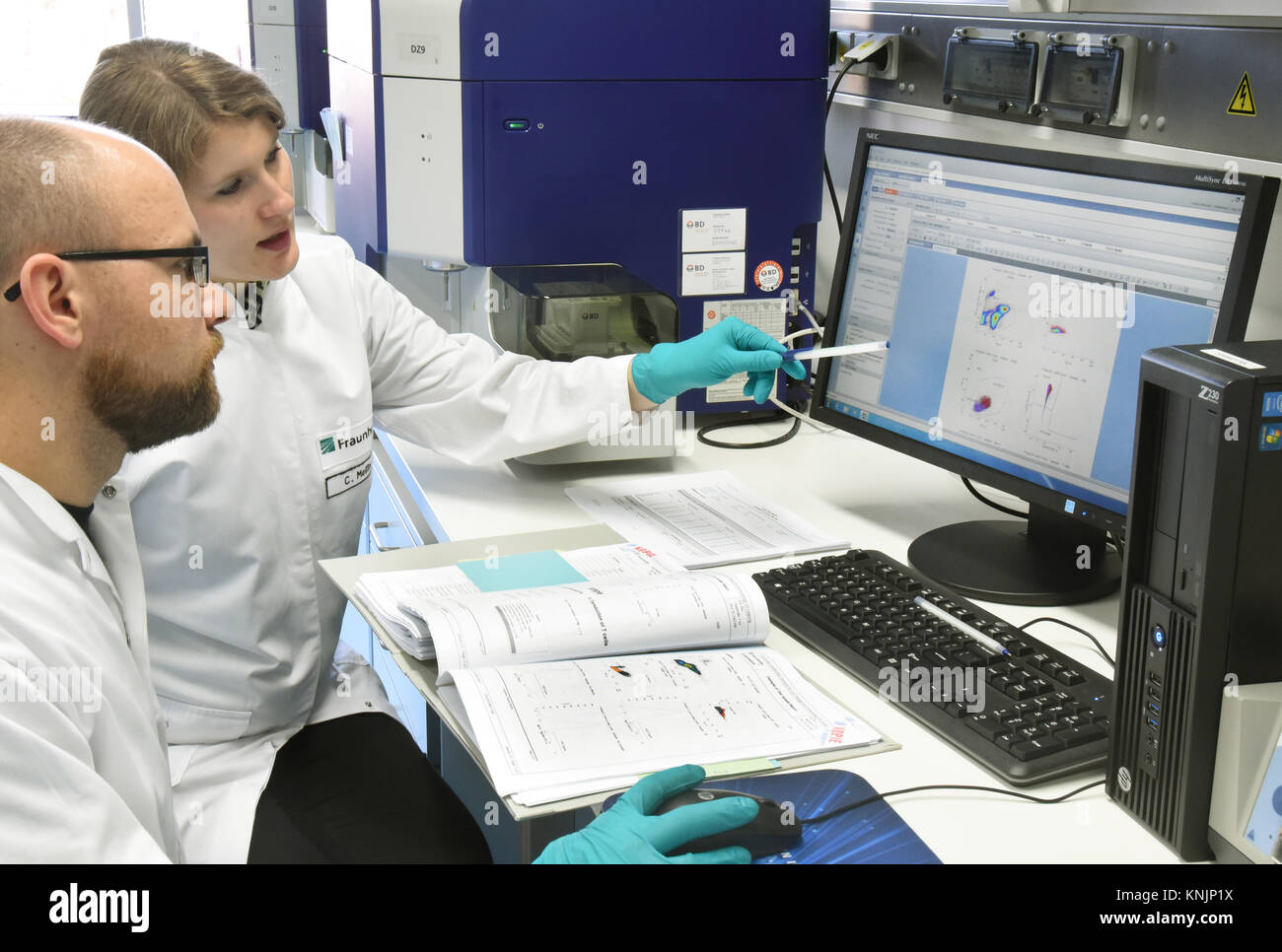 The biochemist Christin Meißner (R) and the medical technical assistant Andreas Kirschner look at surface characteristics of cells for a new form of personalized cell therapy against cancer at the Fraunhofer Institute for cell therapy and immunology (IZI) in Leipzig, Germany, 20 November 2017. The Fraunhofer Institute is working on the joint project with the Novartis Pharma AG in order to properly develop the new form of therapy, the Chimeric antigen receptor therapy (CART). It requires the reprogramming of the patients· own immune cells to treat their cancer. Cancer cells will thus be recogni Stock Photo
