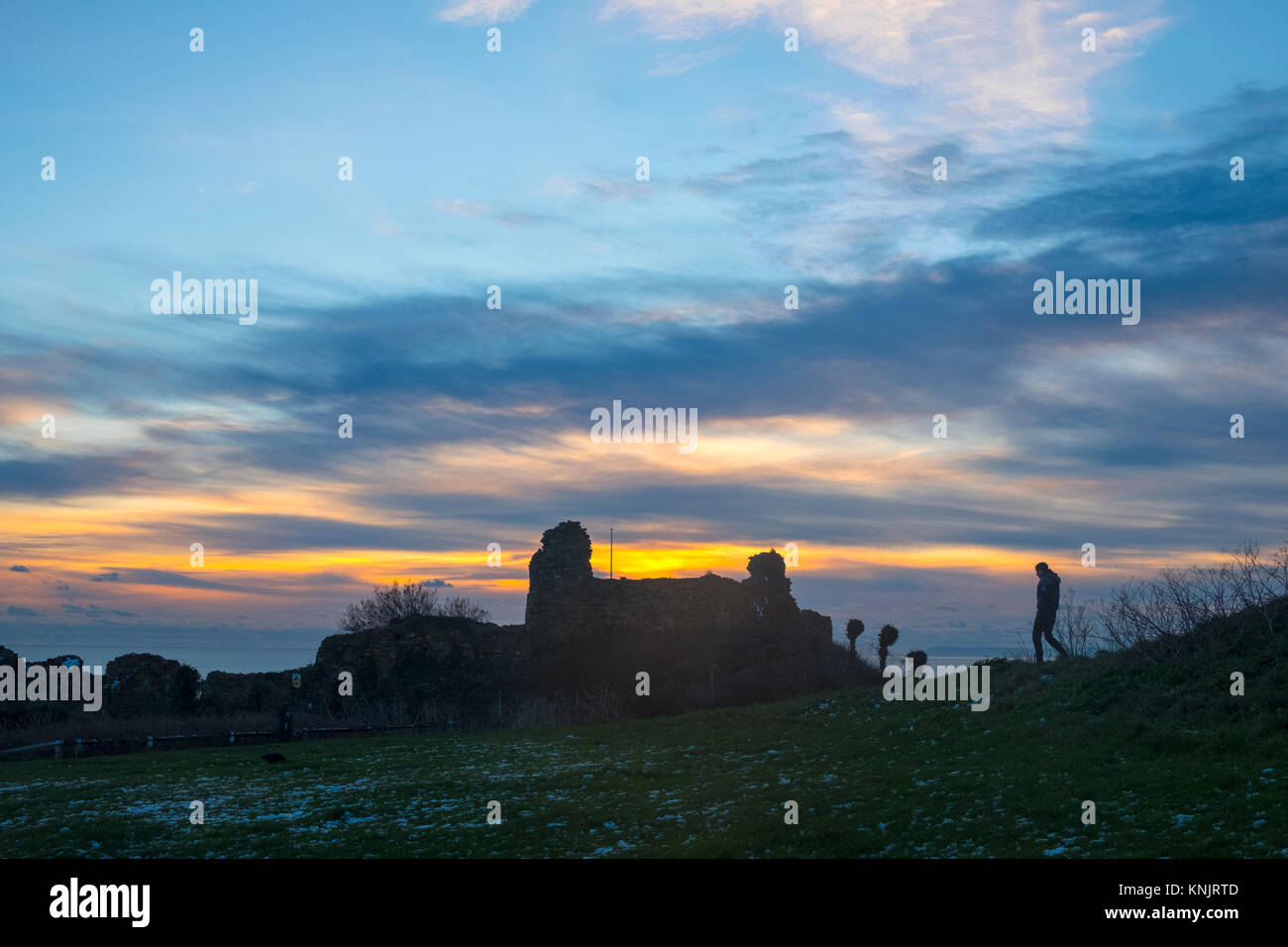 Hastings, East Sussex, 12th December 2017. Walker silhouetted against a winter sunset by Hastings Castle. Stock Photo