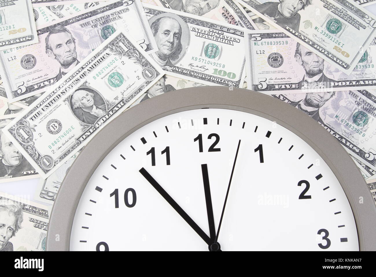 Clock on assorted American banknotes. Time is money idea Stock Photo ...
