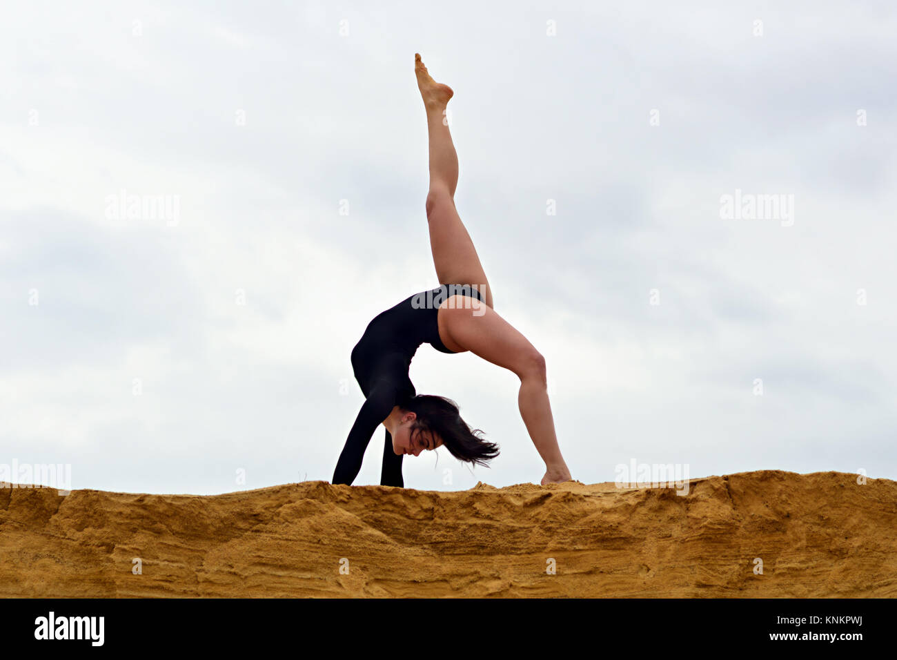 No support stretching of leg muscles with a hand grip (on the background of cloudy sky) Stock Photo