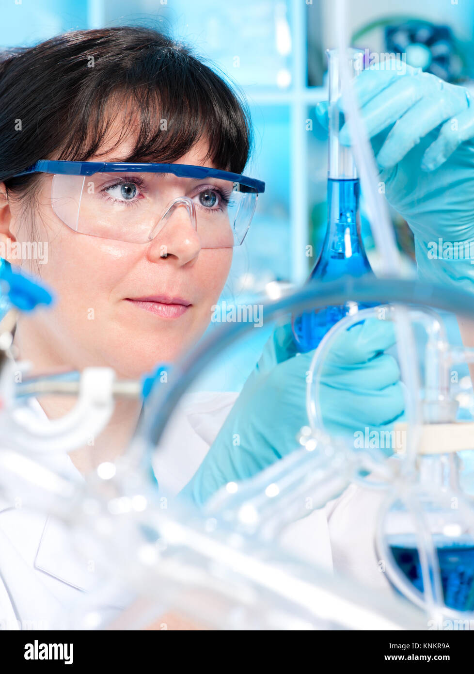 Female tech in protective wear works in chemical lab Stock Photo