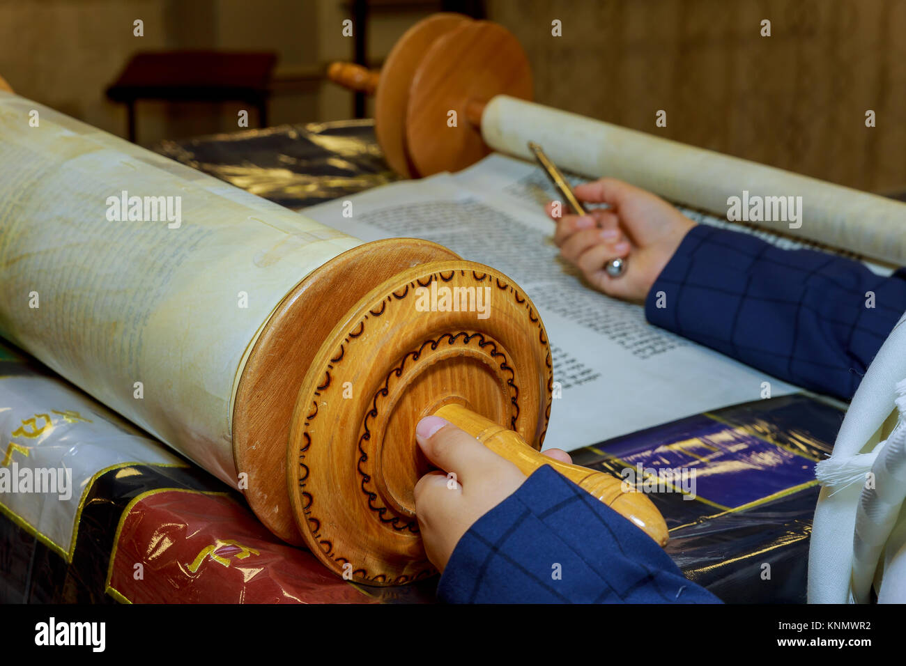 Reading a Torah scroll during a bar mitzvah ceremony with a traditional yad pointing towards the text on the parchment. Stock Photo