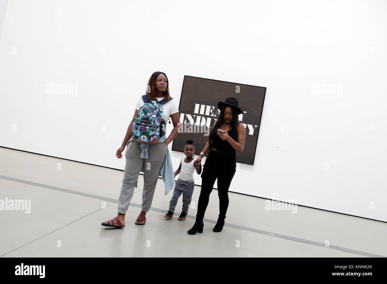 Visitors looking at artwork and woman looking at cell phone inside an art gallery at the Broad Museum in downtown Los Angeles, LA USA  KATHY DEWITT Stock Photo