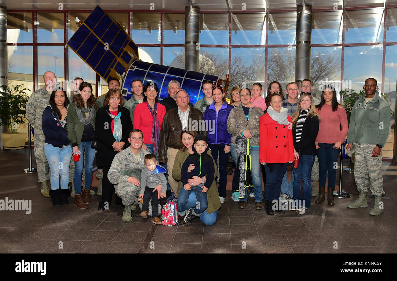 Family members of Team Buckley Airmen pose together in front of a half